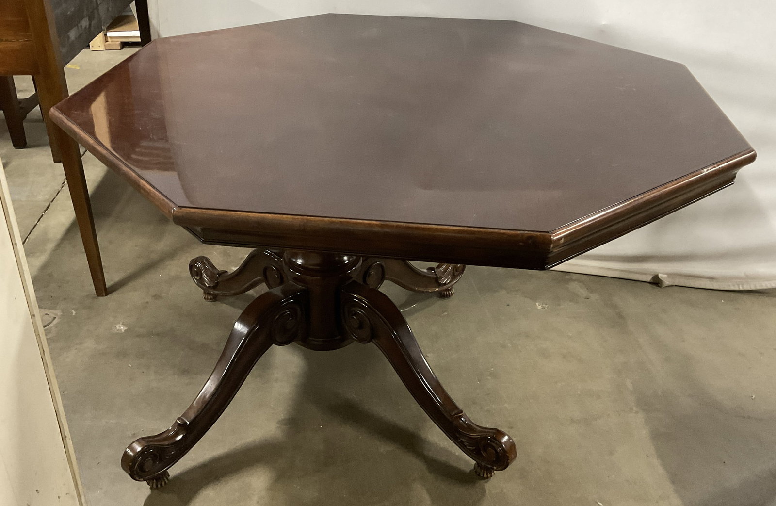 Victorian-Style Polished Wooden Octagon Game Table: Victorian-Style Polished Wooden Octagon Game Table. Dark Wood. Rests on a pedestal with elaborately carved scrolled legs. Top lifts up to reveal storage. Scratching and chipping present. Measures app 