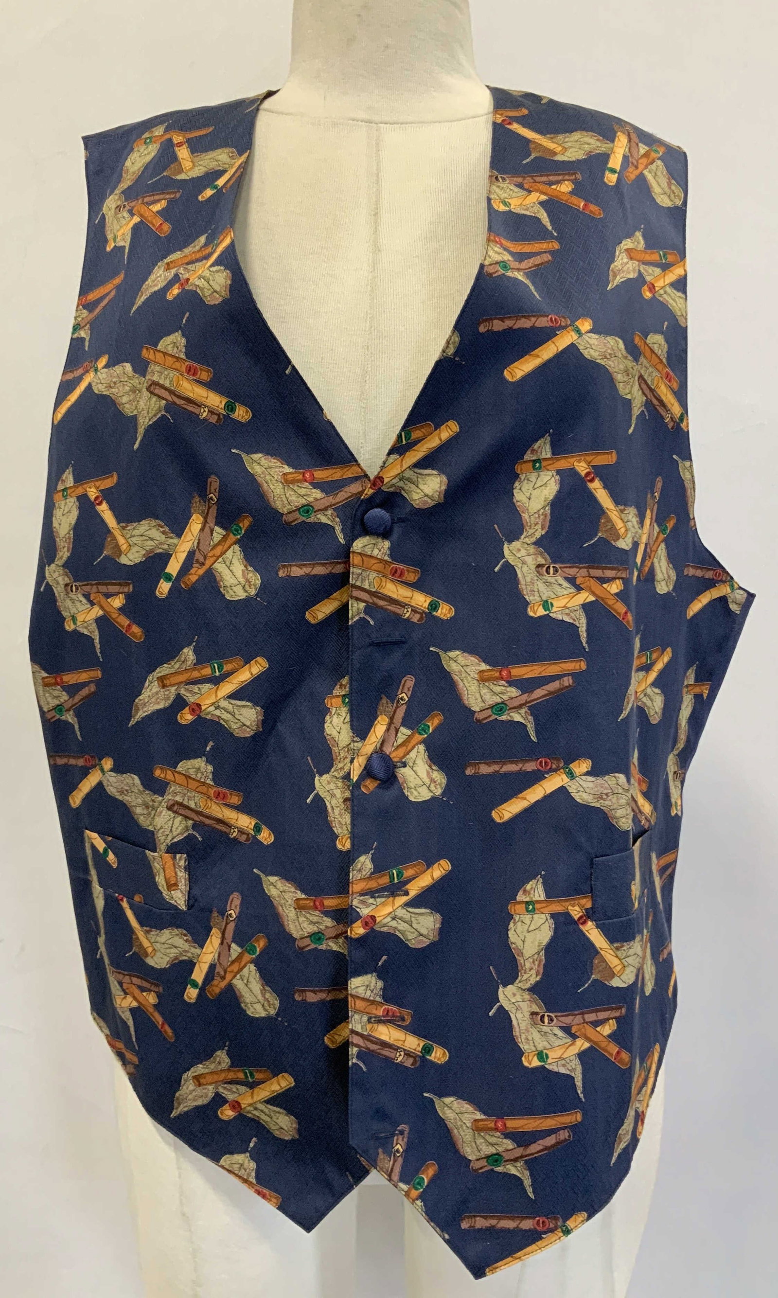 J.W.E. Designs Navy Silk Vest: Size Large. 100% silk. Navy vest features a print of cigars & papers. 2 front pockets. Signed & marked. Reads, J.W.E. DESIGNS. Surface wear consistent to age, use & exposure. J.W.E. Designs silk vest,