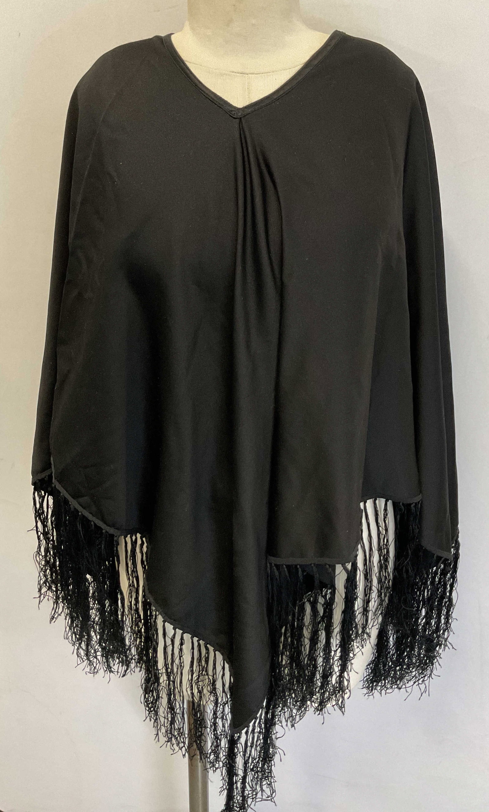 Vintage Black Fringed Sleeveless Shawl: Vintage black fringed sleeveless shawl. Silk material. Black fringed trim. Over the head sleeveless shawl. Measures approx 29 inches across chest. Wear consistent with exposure. Shawl, wearables, clot