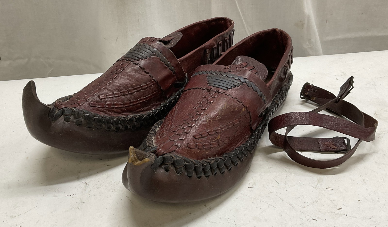 2 Handmade Red Leather-Style Pointed Toe Shoes: 2 Handmade Red Leather-Style Pointed Toe Shoes. Black Braided Trim. Comes with Additional Buckle Accessory. No Visible Size or Markings. Some Surface Wear Such as Scuffing and Peeling Present. Some Lo