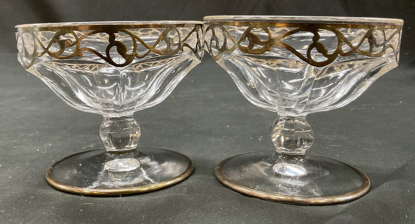 Pair Vtg Glass & Sterling Silver Sherbet Cups: Pair of vintage Art Deco glass and sterling silver sherbet cups. Round base. Faceted stem. Wide rim and faceted body. Sterling silver overlay. Swirl geometric pattern. Measures ht approx 3.5 inches di