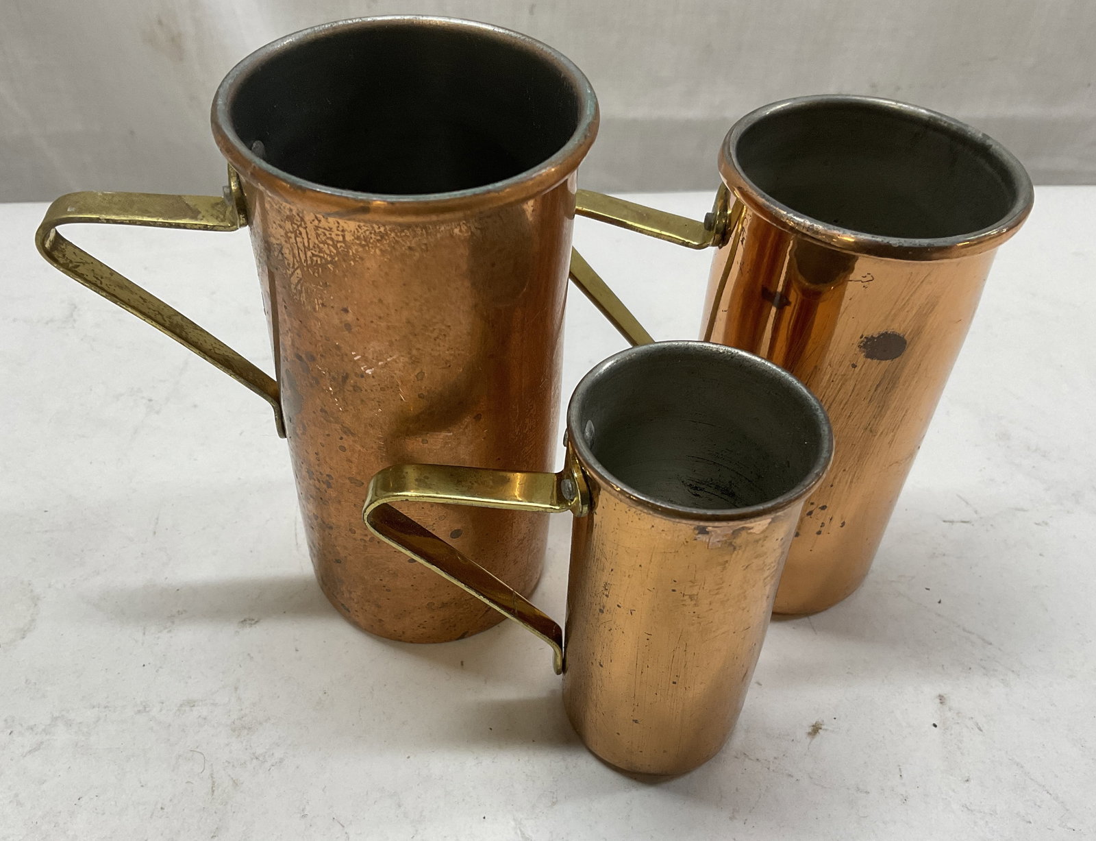 Lt 3 VTG Copper & Brass Measuring Cups: 3 Vintage Copper Measuring Cups with Brass Handles. Includes a 3/4 Cup, 1/2 Cup, and 1/4 Cup. Discoloration, Tarnishing, and Scratching Present. Largest Measures app 4in H x 2in Diameter. Vintage Meas