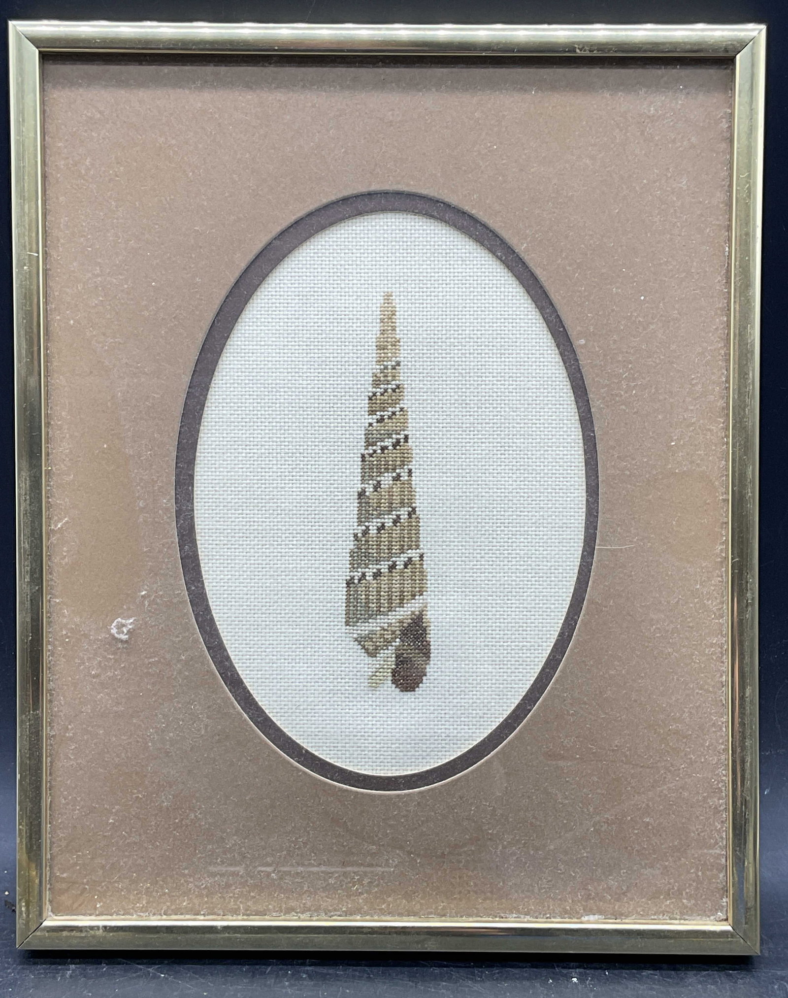 Framed Needlepoint Seashell Panel: Framed and matted needlepoint panel. Seashell motif. Gold tone frame. Not examined out of frame. Frame measures approx. 10.5 x 8.5 inches. Some wear consistent with exposure. Art, framed art,