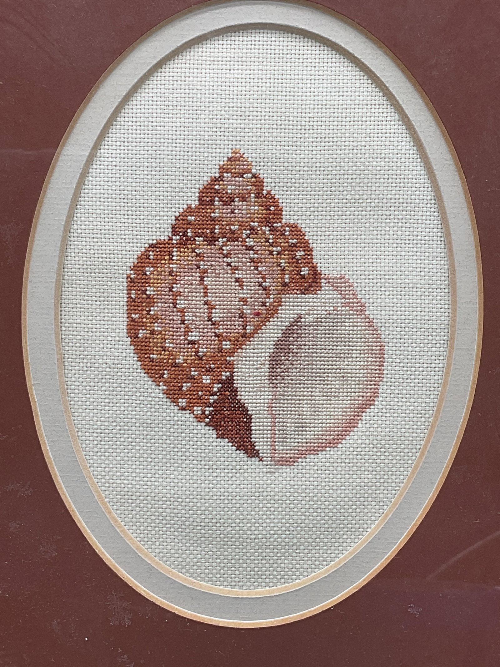 Framed Needlepoint Seashell Panel: Framed and matted needlepoint panel. Seashell motif. Gold tone frame. Not examined out of frame. Frame measures approx. 10.5 x 8.5 inches. Some wear consistent with exposure. Art, framed art,