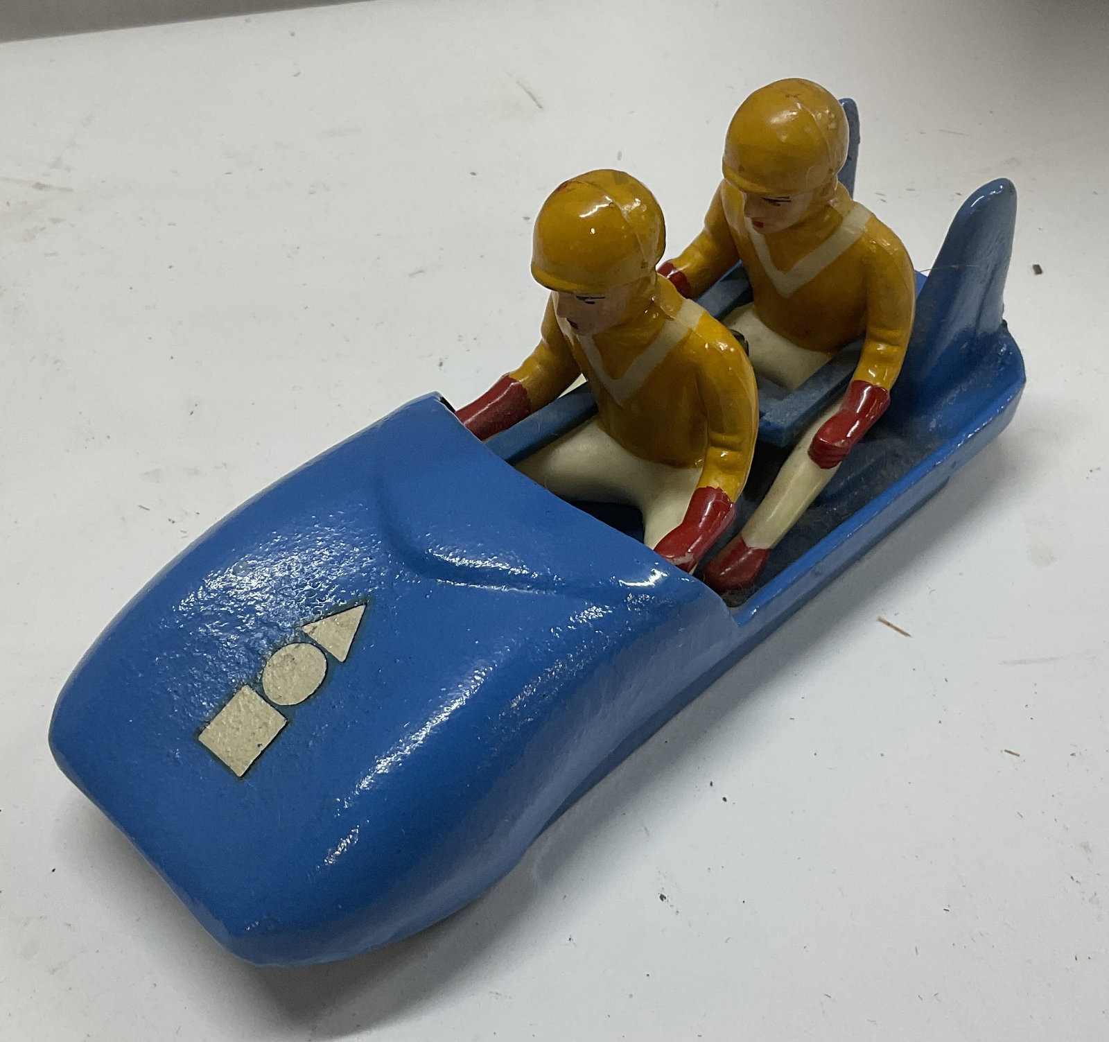 VTG 1950s Karl Heusser Bobsled Toy GERMANY: Vintage 1950s Karl Heusser Hela Bob 2-Man Bobsled Toy. Made in Germany. Painted Blue Cast Iron Bobseld. 2 Resin Riders in Yellow. Comes with Original Papers Printed in German. Aging and Tears Present