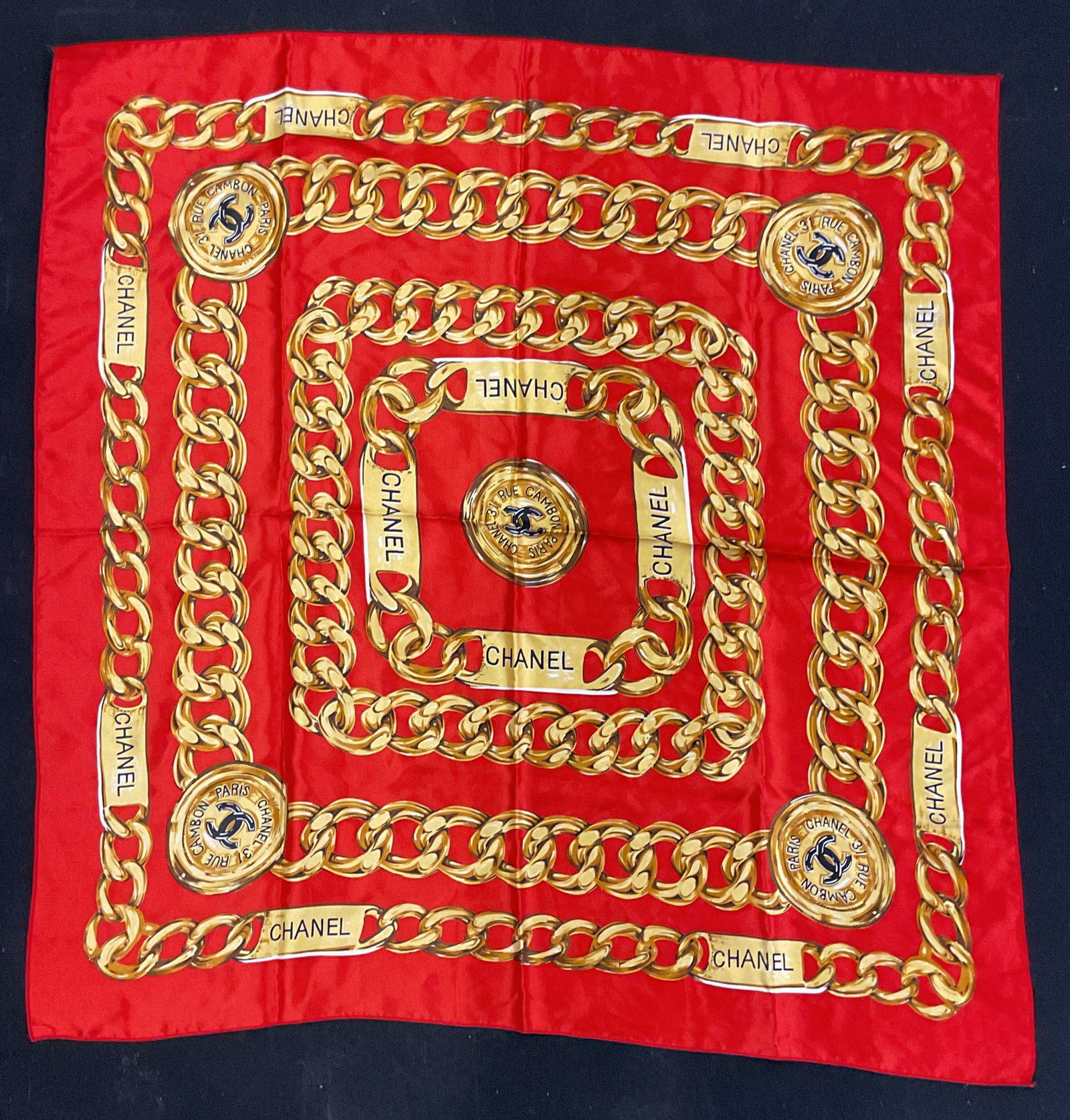 Red Gold Interlocking C Chain Print Scarf: Red and gold interlocking C and chain print scarf. Synthetic material. Measures approx. 34.5 x 33.5 inches. Some blemishes. Interlocking c scarf, chain print scarf, red scarf, accessories, fashion
