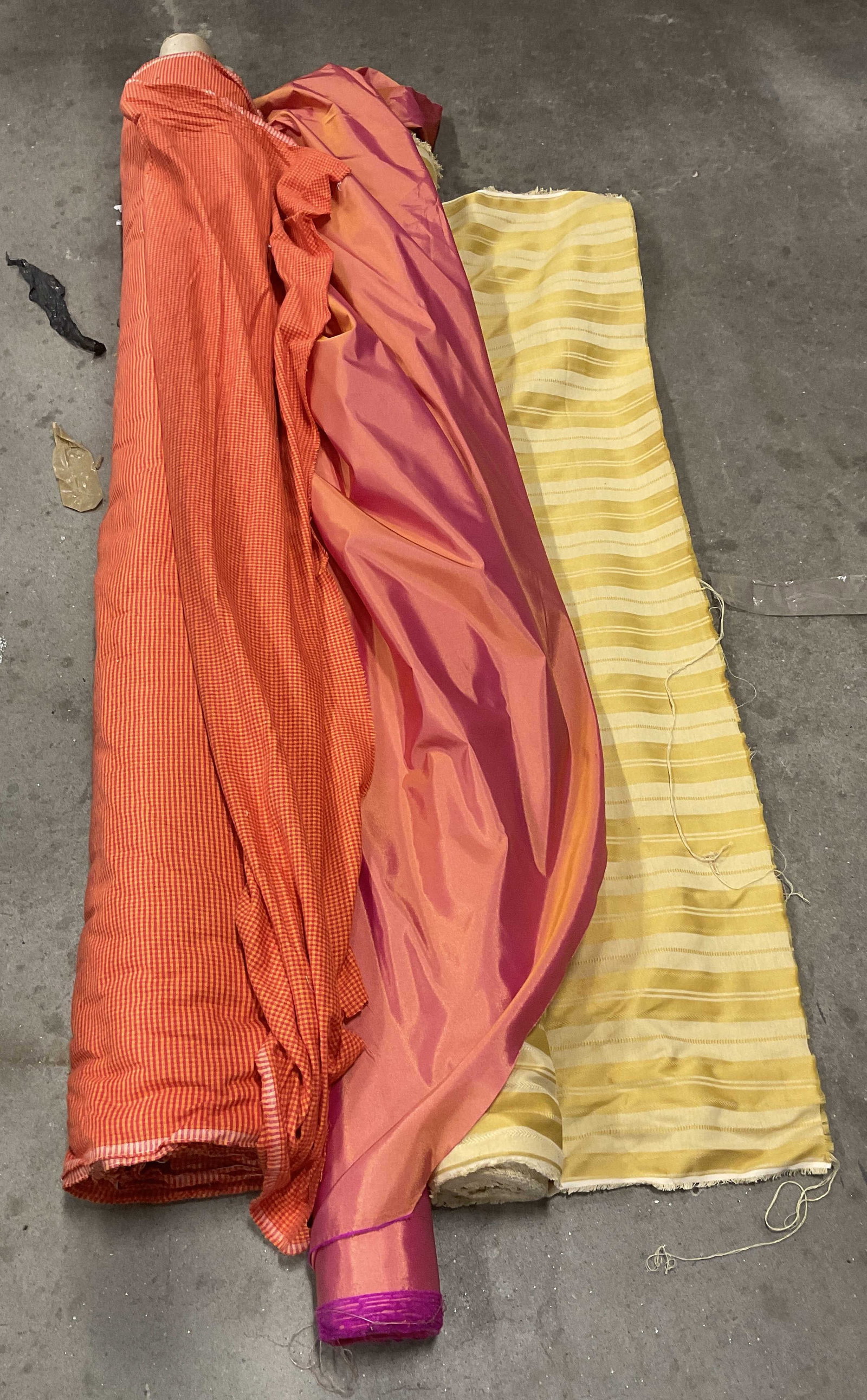 Lt 3 Vibrant Solid & Textured Bolts of Fabric: 3 Vibrant Solid & Textured Patterned Bolts of Fabric. Mixed Materials. Cotton, Silk and More. Orange & Red Checkered, Orange & Pink Shimmery Silk, and Two-Toned Yellow Stripes. Not Measured, Unrolled,