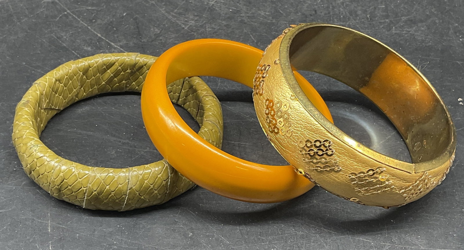 Lot 3 Amber Tone, Snake Embossed, Sequin Bangles: Lot of 3 bangle bracelets. Amber toned acrylic, green snake embossed, and gold tone sequined bangles. All measures approx. 2.5 inches wide. Some scratching. Jewelry, estate jewelry, costume jewelry, c