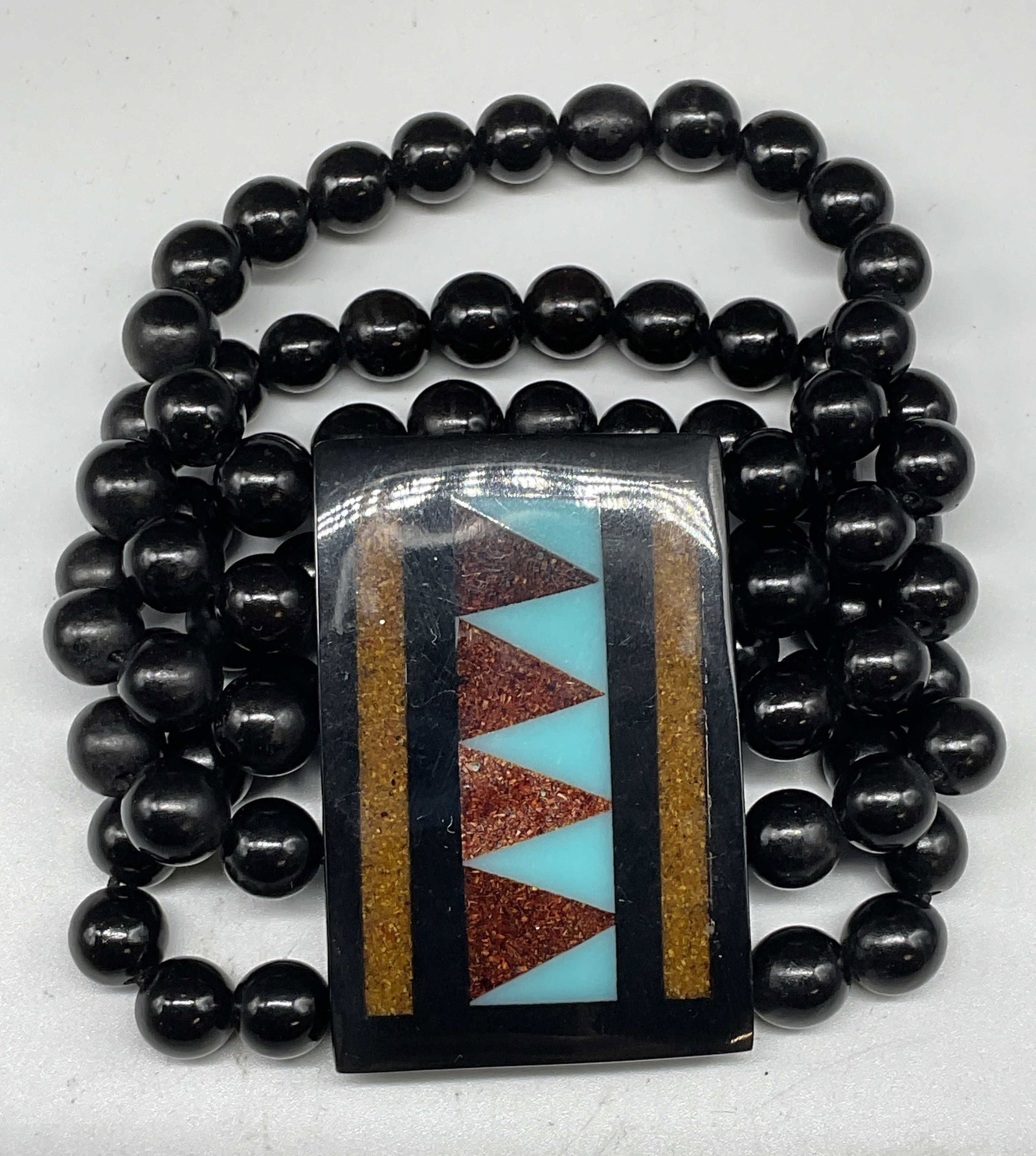 Vtg Black Beaded Inlaid Geometric Bracelet: Vintage chunky black beaded stretch band bracelet with inlaid geometric pattern resin panel. Panel measures approx. 2.25 X 1.5 inches. Some scratching. Jewelry, estate jewelry, costume jewelry,