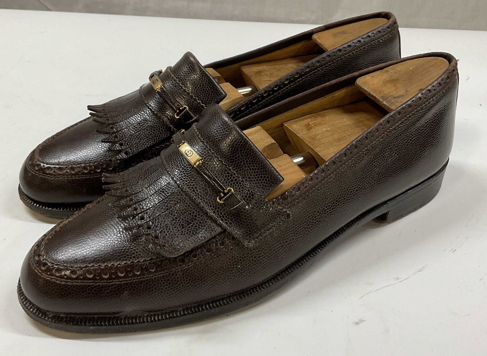 Gucci Brown Leather Fringed Loafers Italy: Gucci brown leather fringed loafers. Marked Italy. Size 42 M. Brown leather. Heeled shoe. Fringed accent with gold toned Gucci logo. Stitching. Some wear. Loafers, Gucci, shoes, wearables, outerwear, 