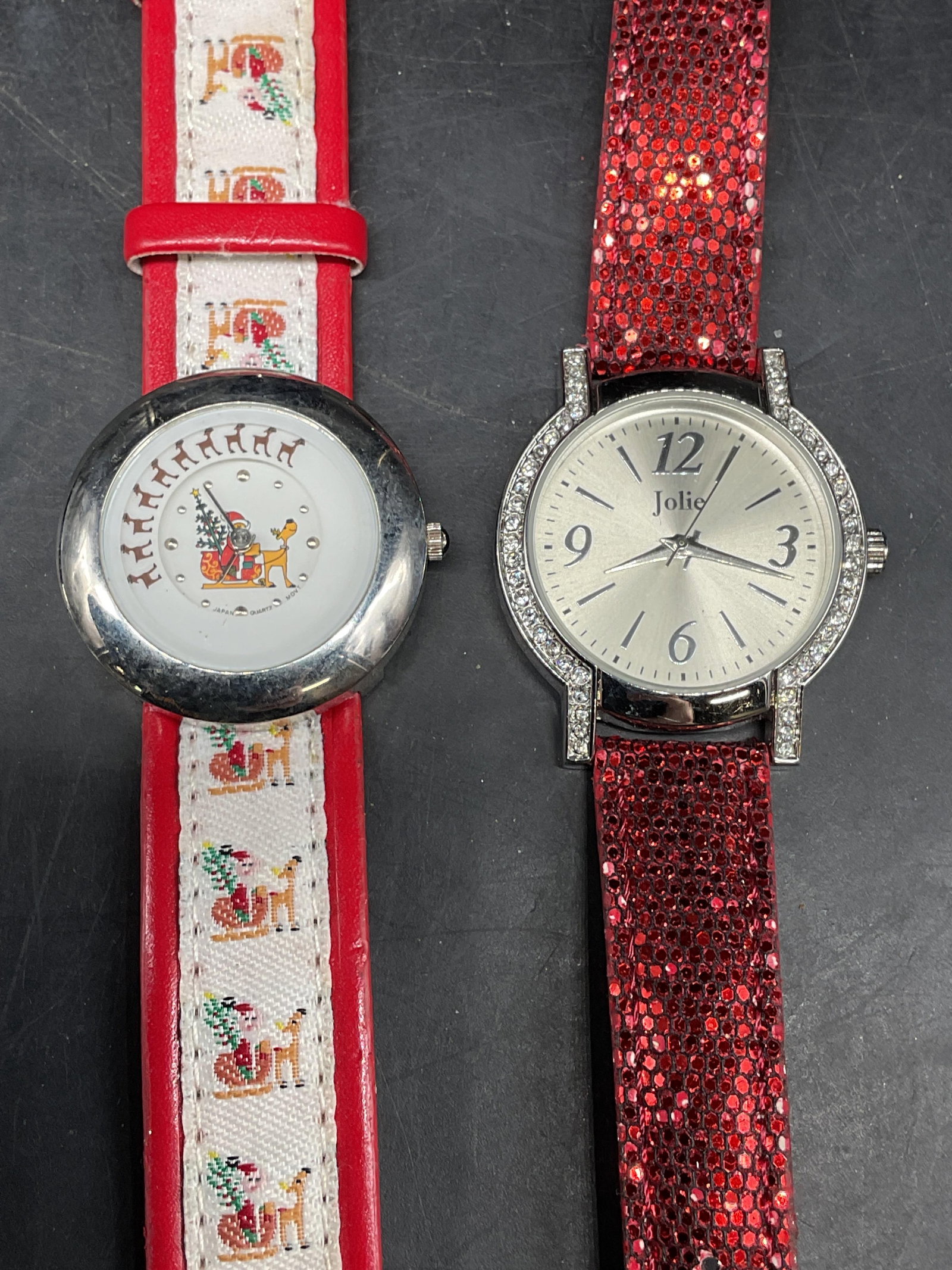 Lot 2 Jolie Sparkly Red Watch, Christmas Watch: Lot of 2 watches. Signed Jolie watch with crystal dial and sparkly red strap. Christmas themes watch with Santa and reindeer dial and strap. Measures approx. 8.5 inches long. Not tested. Some scratchi