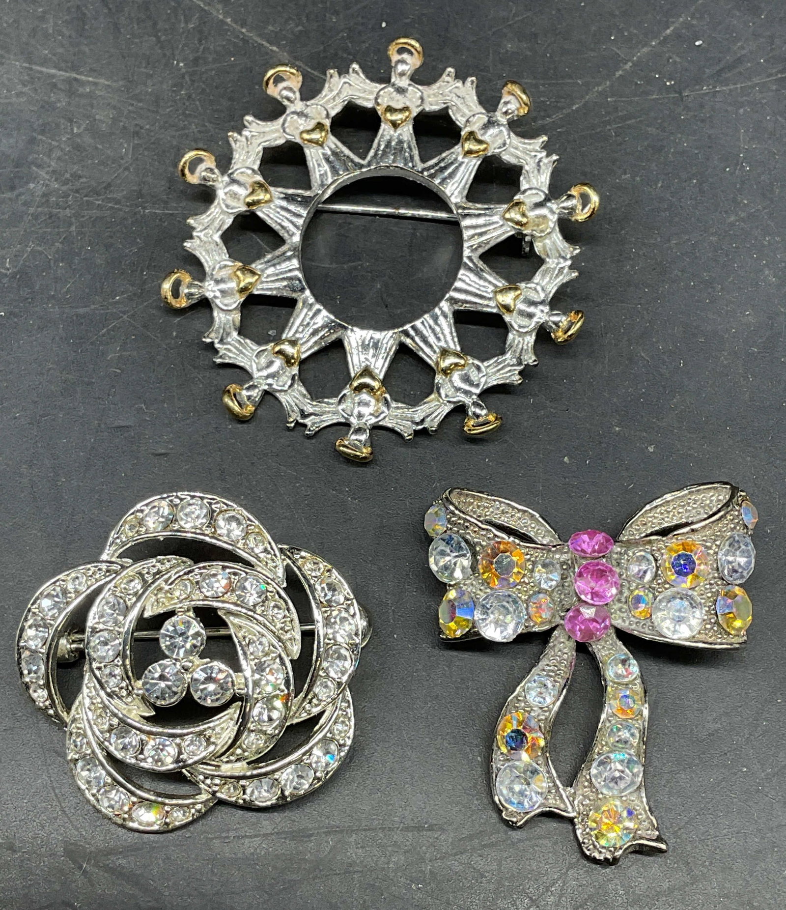 Lot 3 Silver Tn Flower & Bow Crystal Brooches: Lot of 3 silver tone and crystal brooches. 2 flower motif and 1 bow motif. Largest measures approx. 1.75 inches wide. Some scratching. Jewelry, estate jewelry, costume jewelry, cocktail jewelry, fashi
