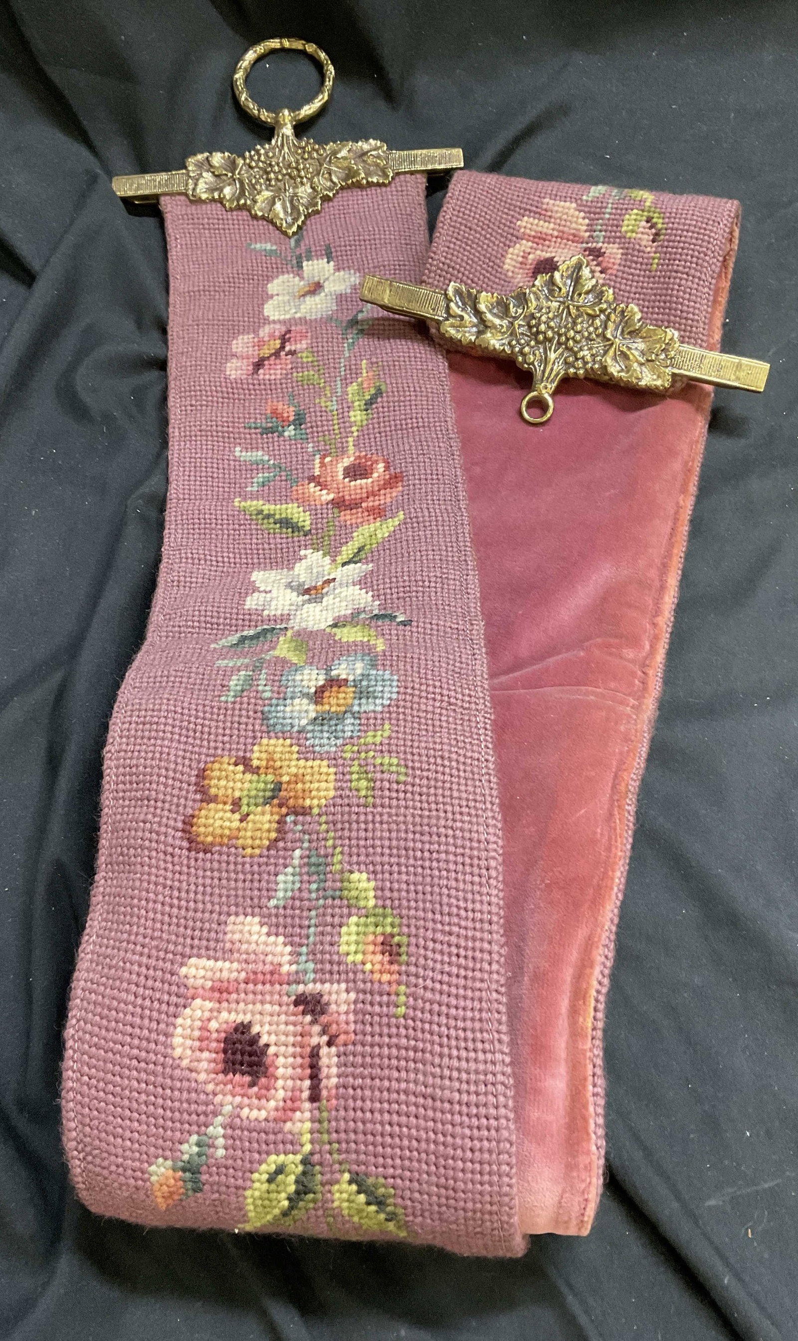 VTG Victorian-Style Floral Needlepoint Bell Pull: Vintage Victorian-Style Floral Needlepoint Bell Pull. Pink Wool with Pink Velvet Backing. Brass Loops with Grapevine Pattern. Some Fading. Measures app 61in L x 5in W. Vintage Bell Pull, Victorian-Sty