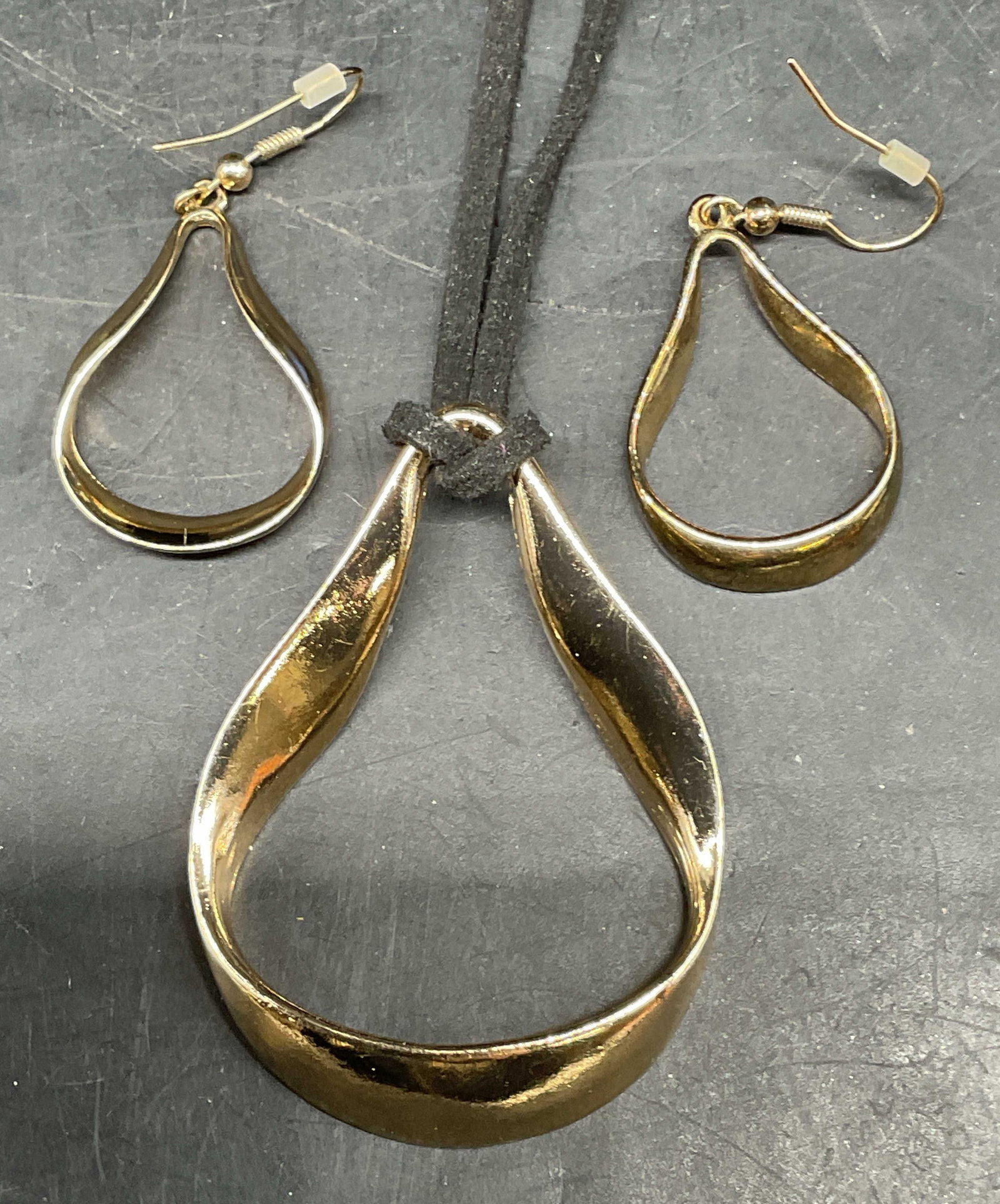 2 Signed C Gold Pendant Necklace & Earrings: Lot of 2 matching jewelry pieces. Signed C gold tone drop pendant necklace its black cord. Drop length 15.5 inches. Matching earrings. Measures approx. 1.25 inches long. Some scratching. Jewelry,