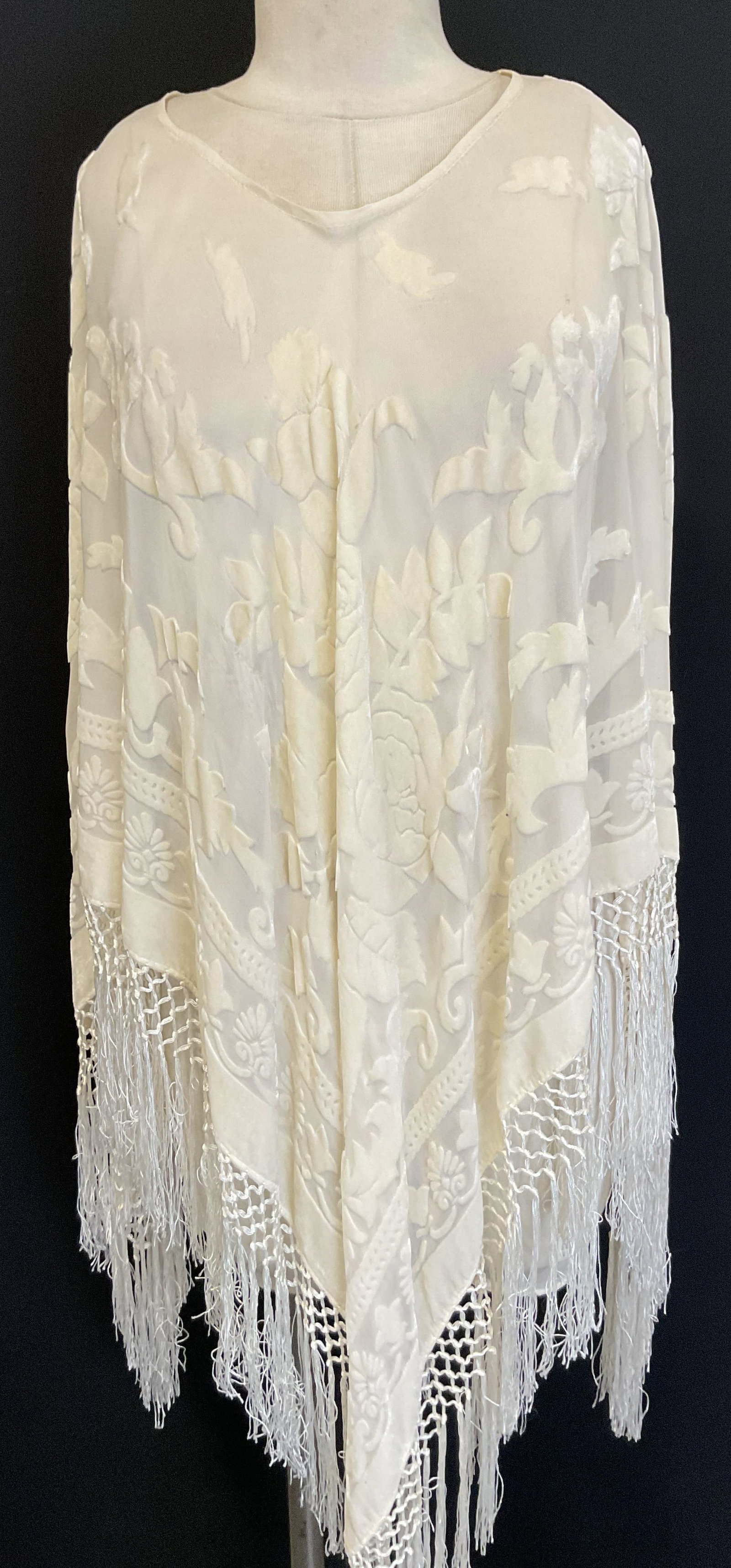 Anis.A White Fringed Sheer Sleeveless Shawl USA: Anis.A white fringed sheet sleeveless shawl. Made in USA. 30% silk 70% viscose. Measures approx 24 inches across chest. White fringed trim. Floral and scroll motif accents. Wear consistent with exposu