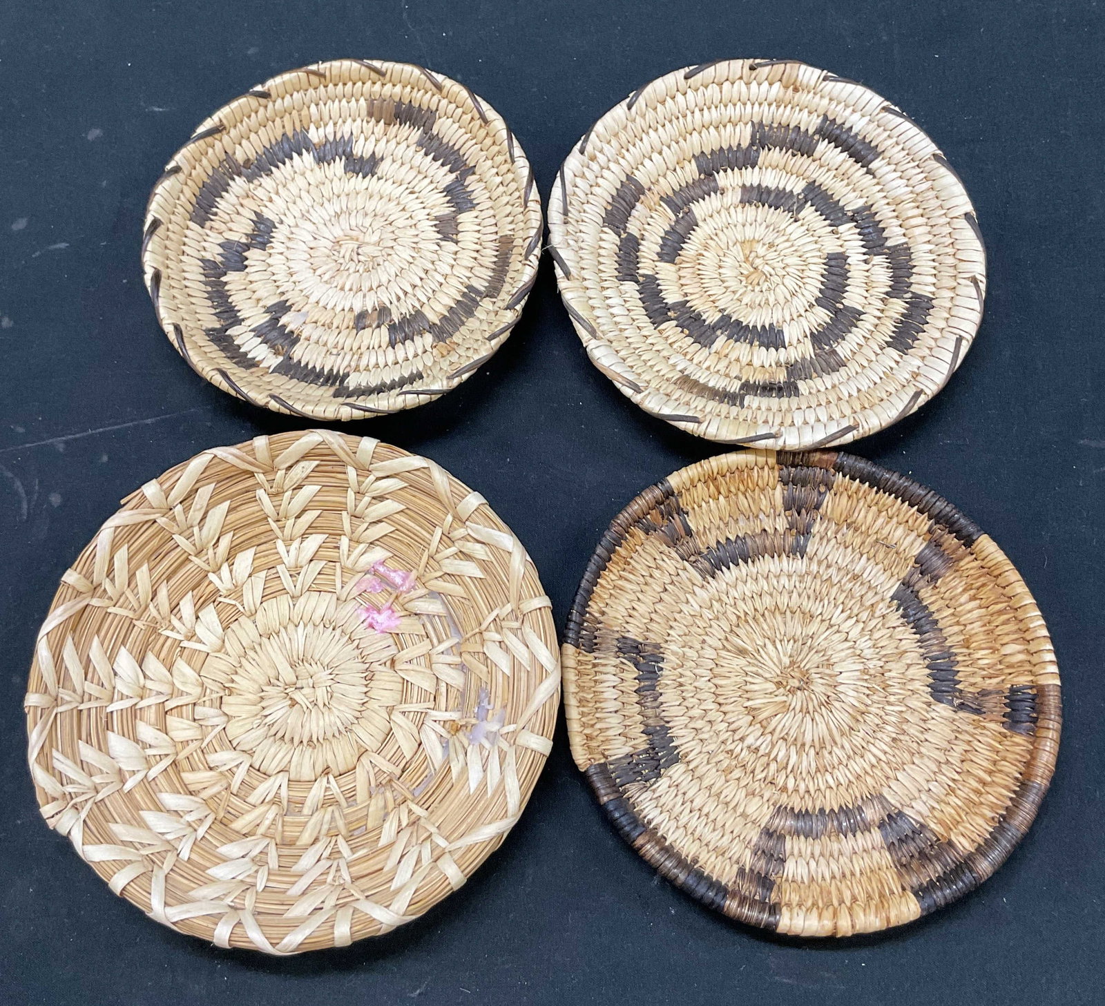 Lot 4 Vintage Woven Coasters: Lot of 4 vintage woven coasters. Round coasters. Geometric woven pattern in light brown and dark brown. Size and design vary. Largest measures approx 5.5 inches in diameter. Surface wear consistent wi