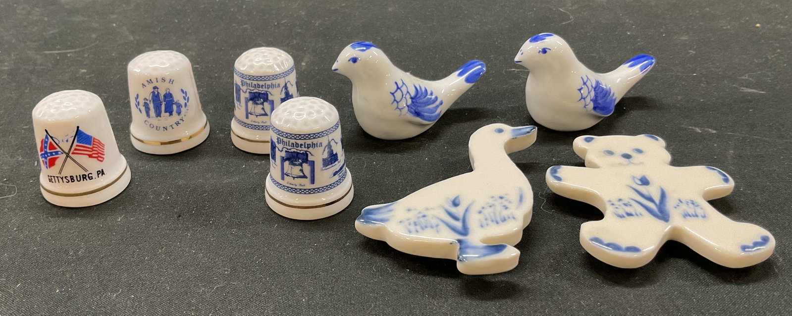Lot8 Russ Berrie&Co+ Porcelain Thimbles&Miniatures: Lot of 8 porcelain items. One is a Russ Berrie & Co. porcelain duck magnet. Other items include bear magnet, two bird figurines, and four souvenir thimbles. The thimbles feature Amish Country, Philade