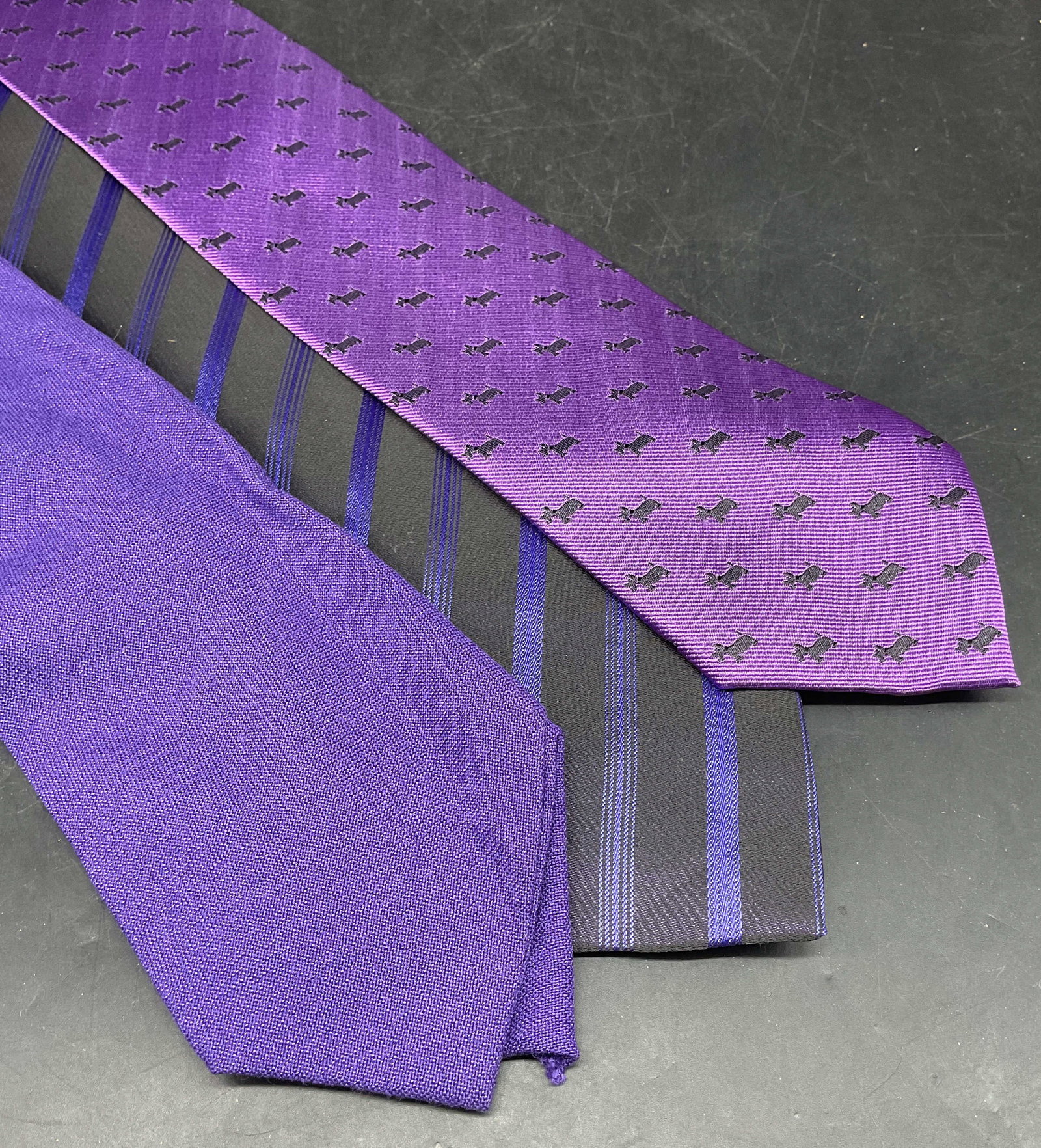 Lot 3 Vicky Sanchez Purple Dog Silk Tie: Lot of 3 ties. Tiez by Vicky Sanchez purple dog print silk tie. Black and purple striped silk tie. Solid purple tie, synthetic material. Longest measures approx. 58 inches. Some blemishes. Tie, silk t