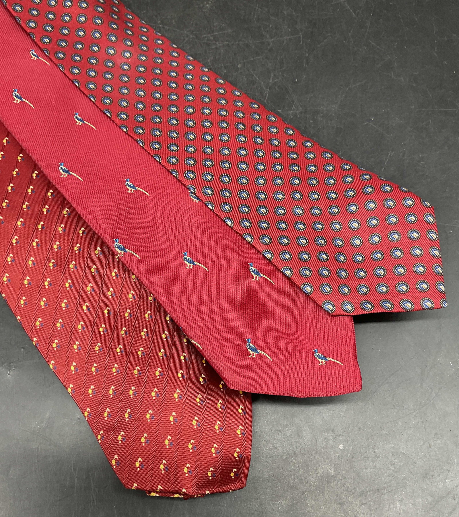 Lot 3 Geoffrey Beene Red Silk Tie +: Lot of 3 red ties. Geoffrey Beene geometric print silk tie, Cambridge Collection triacetate tie, Egon Von Furstenberg bird print polyester tie. Longest measures approx. 54 inches. Some blemishes. Tie,