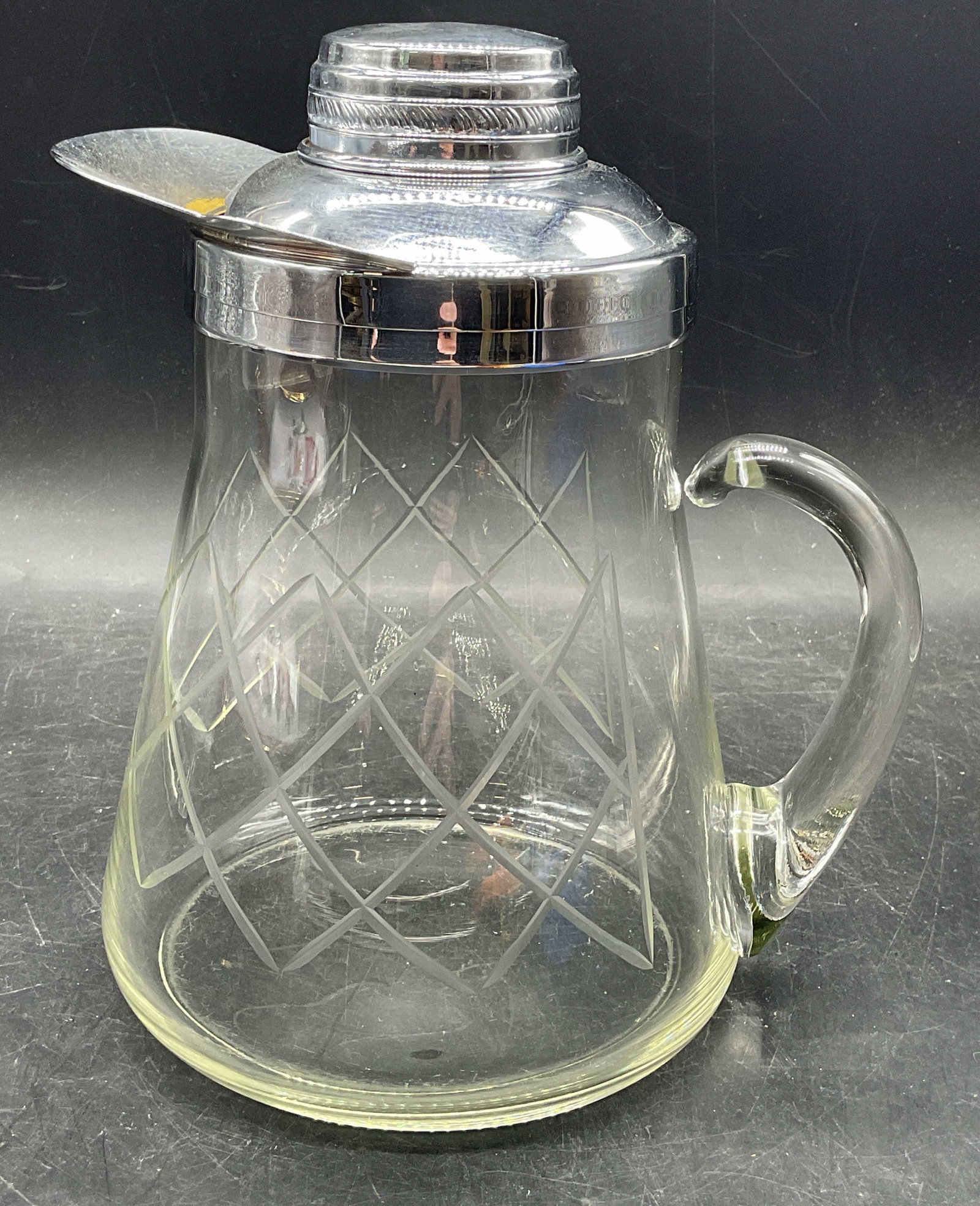 Vintage Cut Art Glass Pitcher: Vintage art glass pitcher with silver tone rim and applied handle. Cut diamond pattern. Measures approx. 7.5 x 6 x 9 inches. Some scratching. Art glass pitcher, cut glass pitcher, tableware, table acc