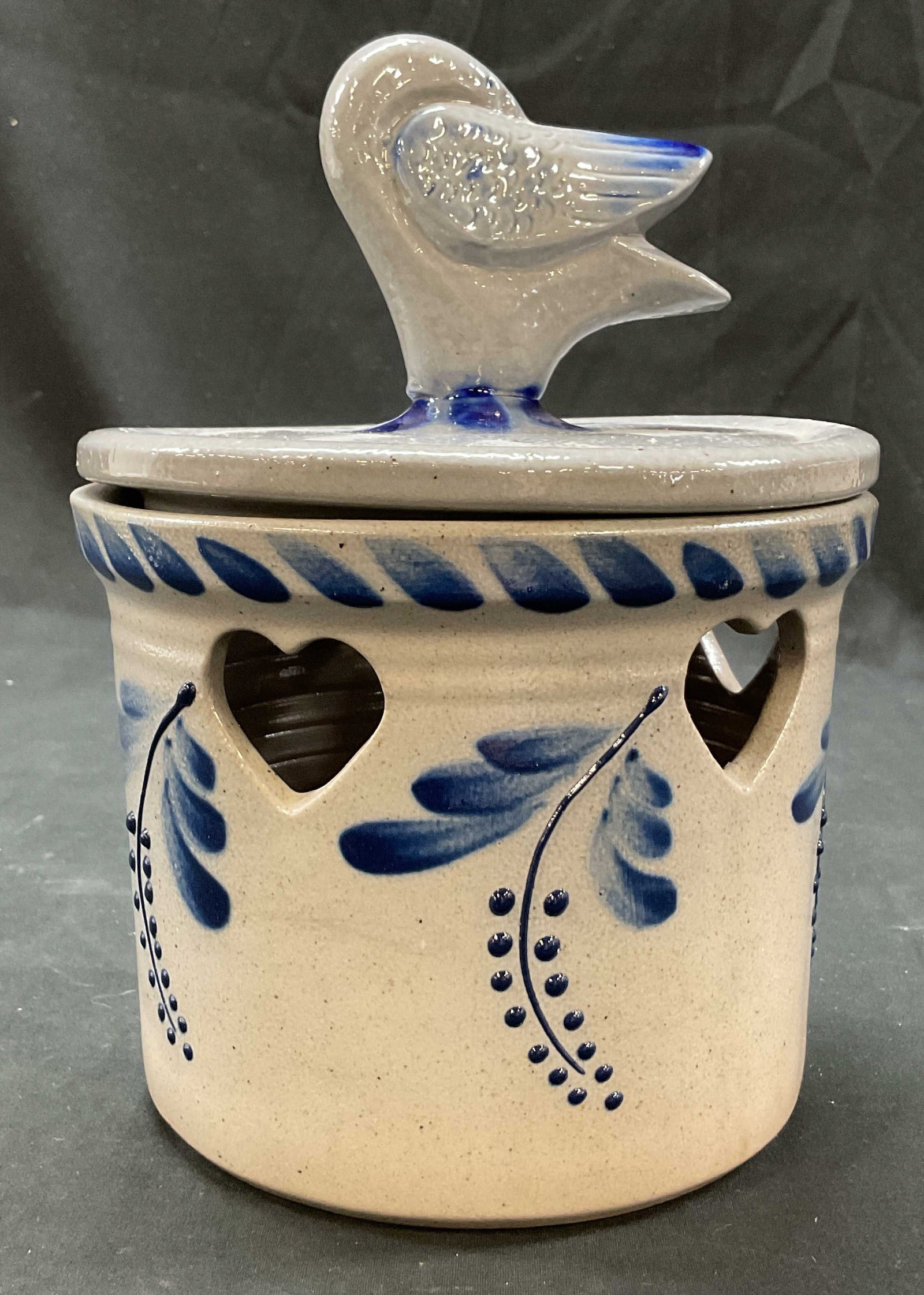 1993 David Eldreth Stoneware Lidded Crock USA: 1993 David Eldreth stoneware lidded crock. Marked on underside, reads David Eldreth Nottingham PA 1993. Tall round shape. Salt glaze finish. Heart shape cut outs. Hand painted blue berry and leaf moti