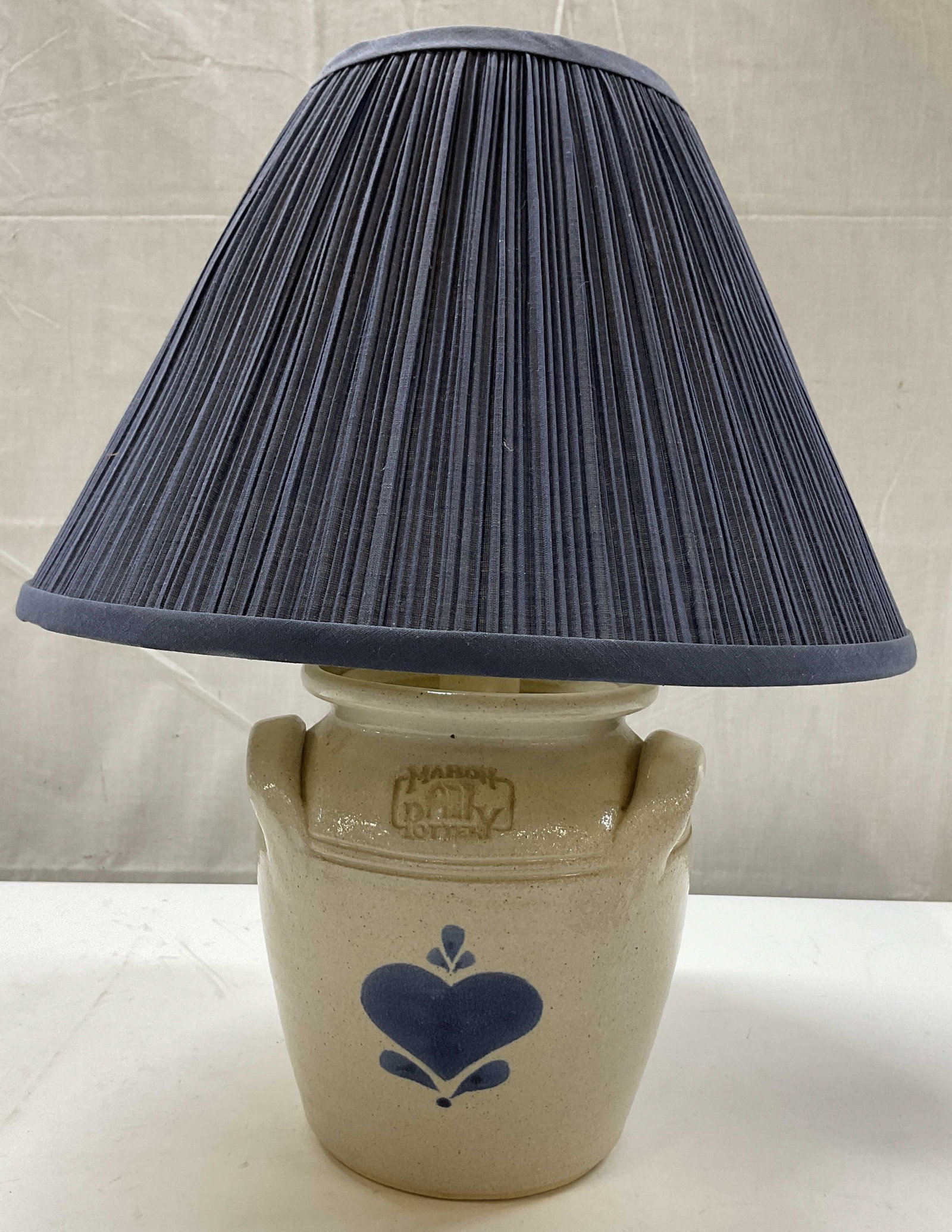 Mahon Pottery Stoneware Lamp Base W Shade: Mahon Pottery Works stoneware lamp base. Marked on surface, reads Mahon Pottery. Curved handles on either side. Salt glaze finish. Hand painted blue heart motif. Comes with blue pleated shade. Measure
