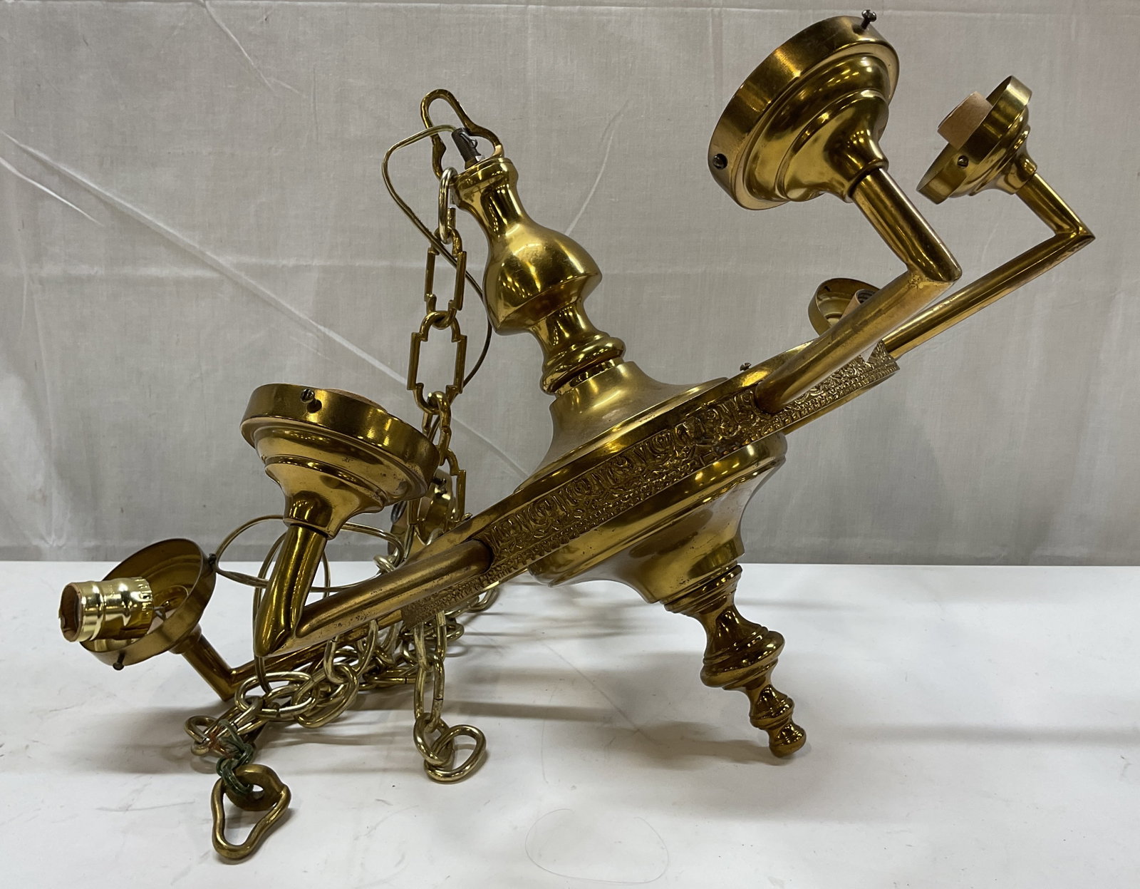Vintage Six Arm Brass Chandelier: Vintage six arm brass chandelier. Six arms extending outwards with light sockets. Decorative finials. Embossed floral and scroll motifs. Some weight. Comes with attached chain link. Measures ht approx