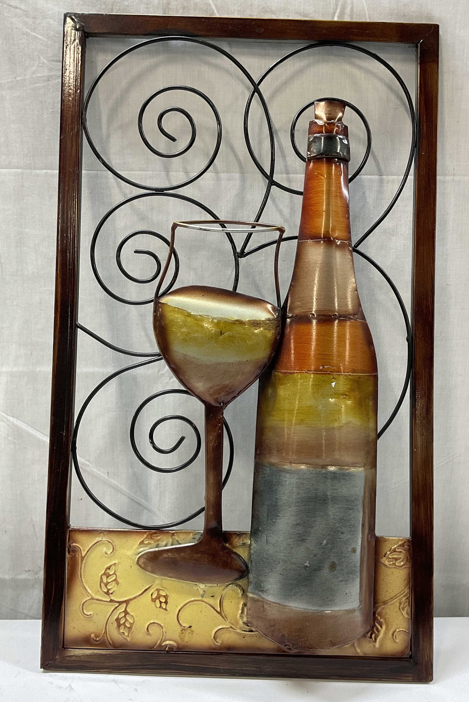 Vintage Metal Wine Wall Decor Sign 24in: Vintage metal wine wall decor sign. Rectangular shape. Swirled accents. Wine glass and bottle. Leaf motifs. Varying colors, hand painted. Thick frame. Measures approx 14 x 24 inches. Some scratching. 