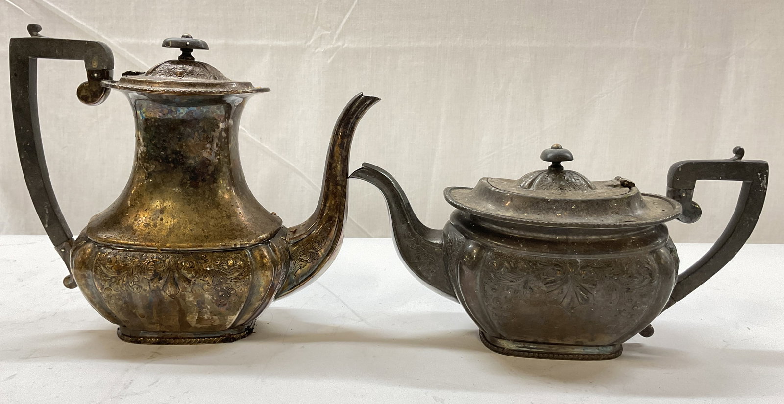 Lot 2 Antq Silver Plated Lidded Teapots England: Lot of 2 antique silver plated lidded teapots. Marked on underside, reads Made In Sheffield England. Curved handles and spout. Embossed floral and scroll motifs. Decorative finial. Size vary. Measures