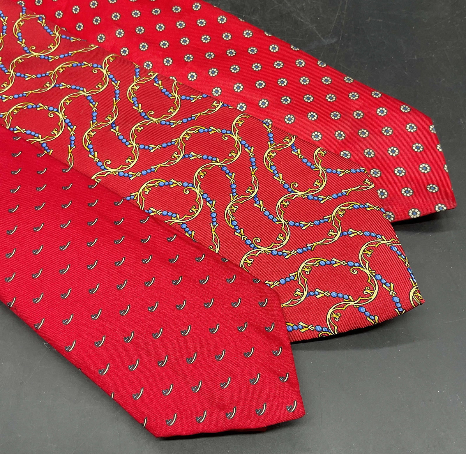 Lot 3 Henri Christian + Red Silk Ties: Lot of 3 vintage red silk ties with graphic prints. Henri Christian, Hardy Amies, and Gino Coyolli. Longest measures approx. 56 inches. Some blemishes to all. Tie, silk ties, red tie, designer tie acc