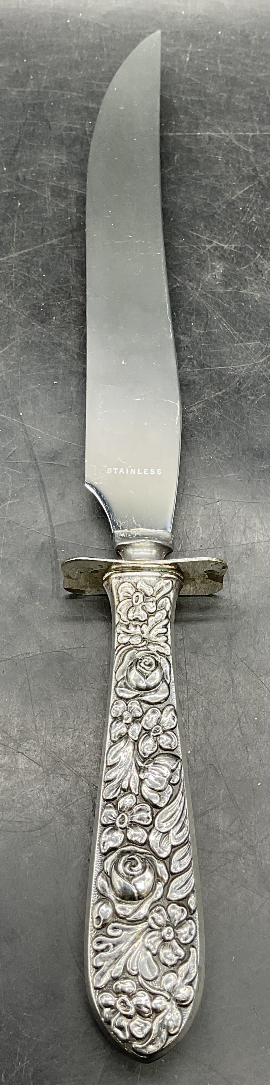 Sterling Silver Repousse Floral Carving Knife: Carving knife with sterling silver handle and stainless steel blade. Marked sterling. Style of Kirk Stieff, no signature or marking. Raised repousse floral design. Measures approx. 13 inches long. Tot