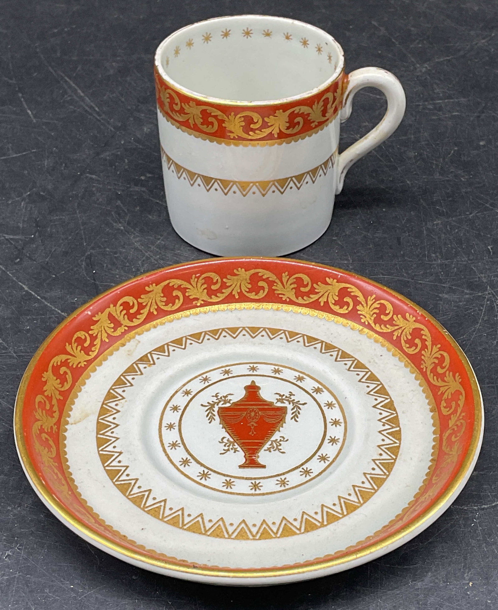 Vtg MINTONS Porcelain Demitasse & Saucers England: Vintage, possibly antique, MINTONS porcelain demitasse cup and saucer. Orange its urn and scroll motif. Gilt decoration. Made in England. Demitasse measures approx. 2 x 2 inches. Saucer measures