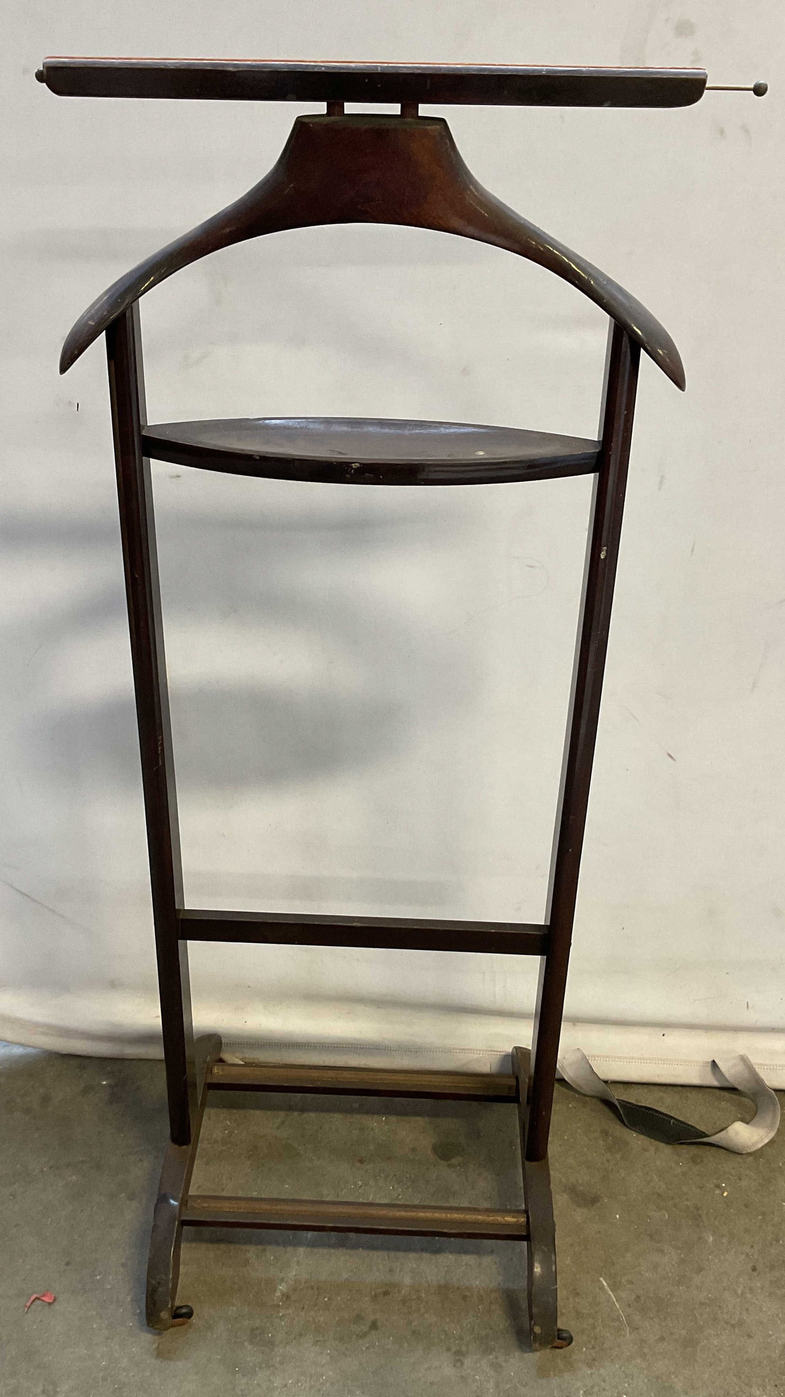 Vintage Wooden Valet Stand Italy 44in: Vintage wooden valet stand. Marked made in Italy. Broad hanger at top. Horizontal bar hanger below. Oval shaped tray. Supported by four wheels. Measures approx 14 x 15 x 44 inches. Some scratching. Va