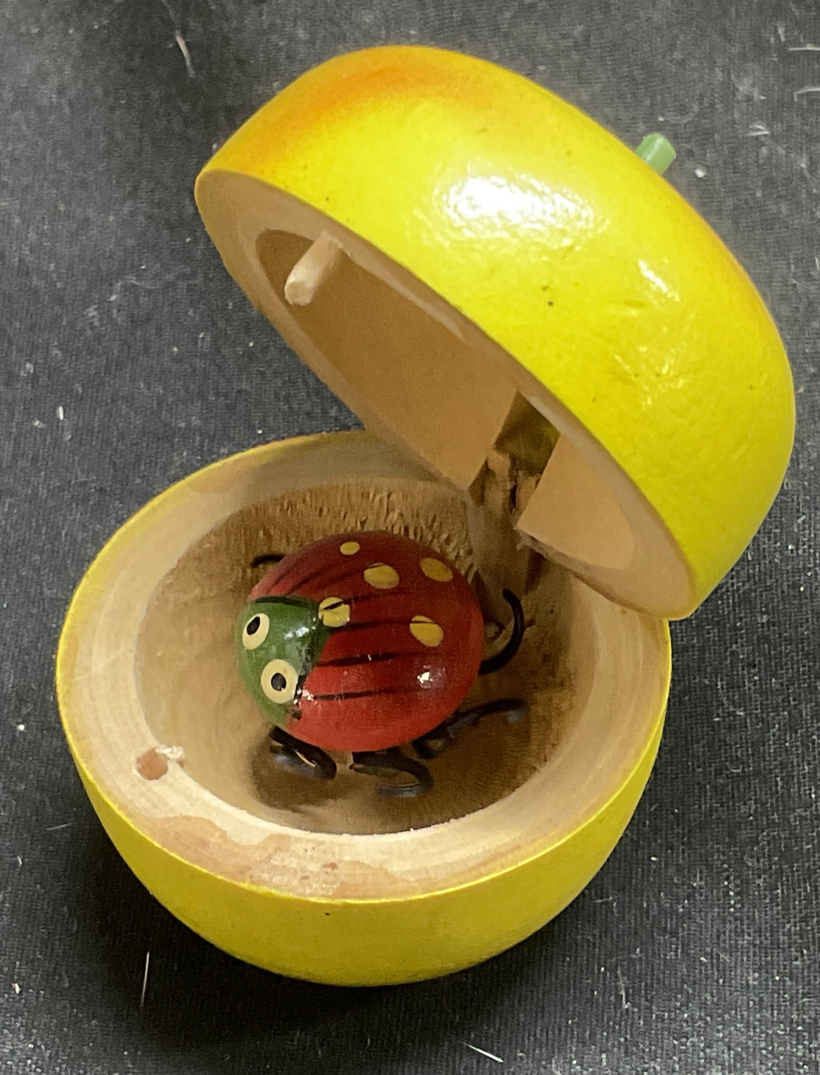 Vintage Wooden Bug in Apple Box Souvenir: Vintage Wooden Bug in Box Souvenir. Box is Golden Delicious Apple-Shaped. Bugs Legs Wiggle. Condition Consistent with Exposure. Measures app 2in H x 1in Base. Vintage Bug in Box, Apple-Shaped,