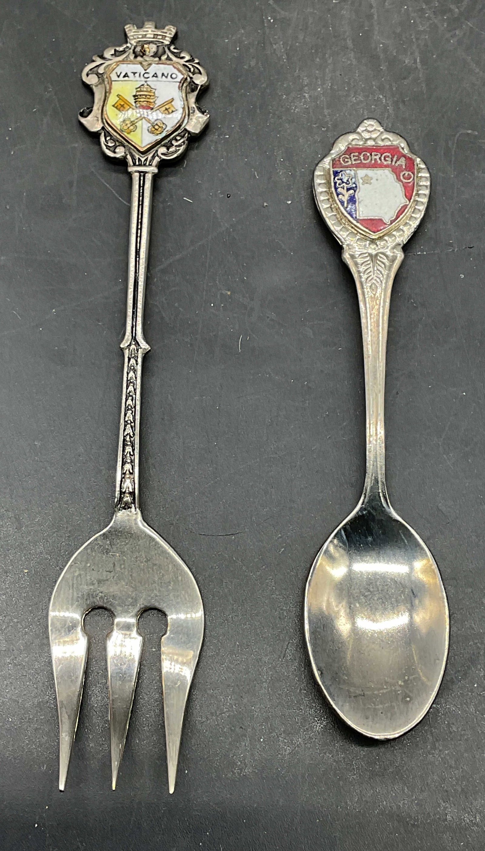 Lot 2 Vatican & Georgia Souvenir Fork & Spoon: Lot of 2 souvenir utensils. Silver plated and enameled Georgia and Vatican motifs. Larger measures approx. 4.25 inches long. Some scratching. Souvenir spoon, souvenir fork, collectibles, Vatican fork,