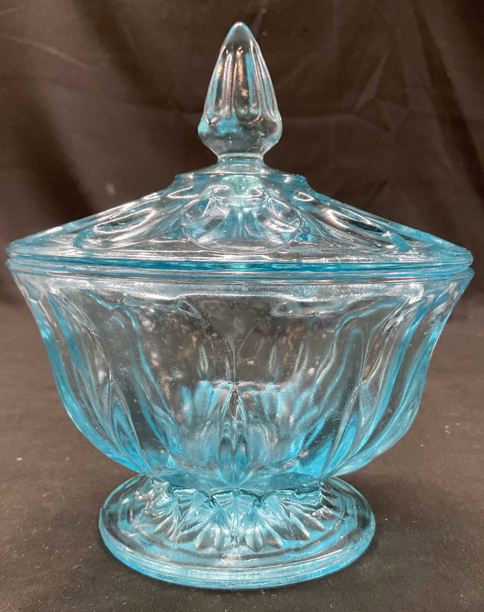Anchor Hocking Fairfield Glass Lidded Candy Dish: Anchor Hocking Fairfield blue glass lidded candy dish. Round pedestal base. Bulbous ribbed and faceted body. Embossed geometric pattern and decorative finial. Light blue tint. Measures ht approx 7 inc