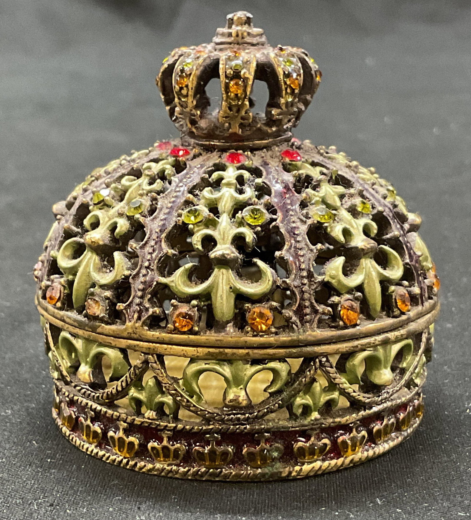Vintage Enameled Brass Kings Crown Trinket Box: Vintage enameled brass kings crown hinged trinket box. Shaped like a crown. Intricate scroll motifs. Accented with rhinestones. Varying colors. Measures ht approx 2.5 inches diam approx 2.5 inches.