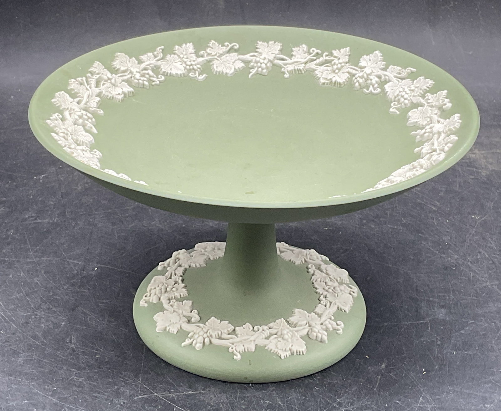 Wedgwood Green Jasperware Tazza, England: Wedgwood green Jasperware footed pedestal tazza with white grapevine relief. Made in England. Measures approx. 6 x 3.5 inches. Some scratching. Wedgwood tazza, collectibles, home decor, table decor,