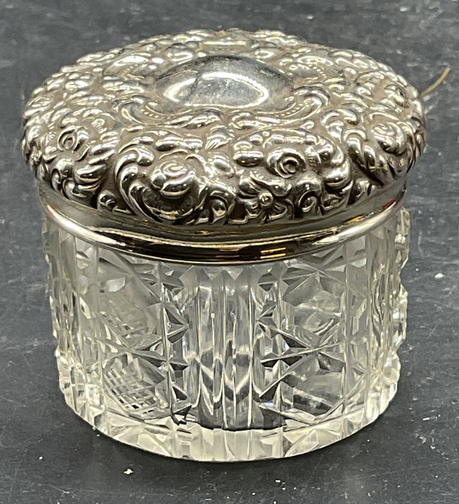 Vintage Sterling Silver Hand Cut Glass Jar: Vintage hand cut glass jar with sterling silver lid. Ornate floral repousse lid. Crosshatch, diamond, ribbed cut pattern jar. Marked sterling. Total weight of sterling 7 grams. Measures approx. 2 x