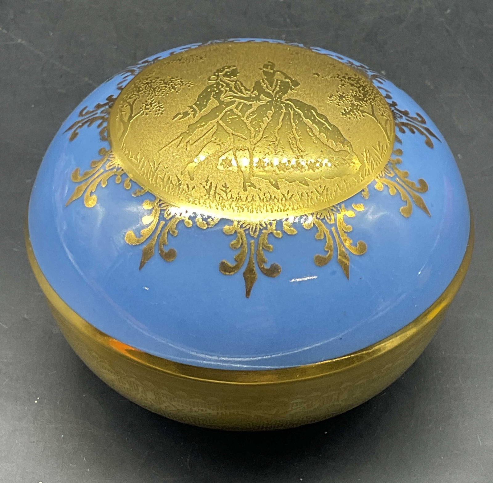 DW Porzellan Gilt Porcelain Trinket Box: DW Porzellan Karlsbader Wertarbeit porcelain trinket box. Blue with ornate gilt decoration. Courting couple motif. Measures approx. 3.25 x 2.5 inches. Some scratching. Dw Porzellan trinket box,