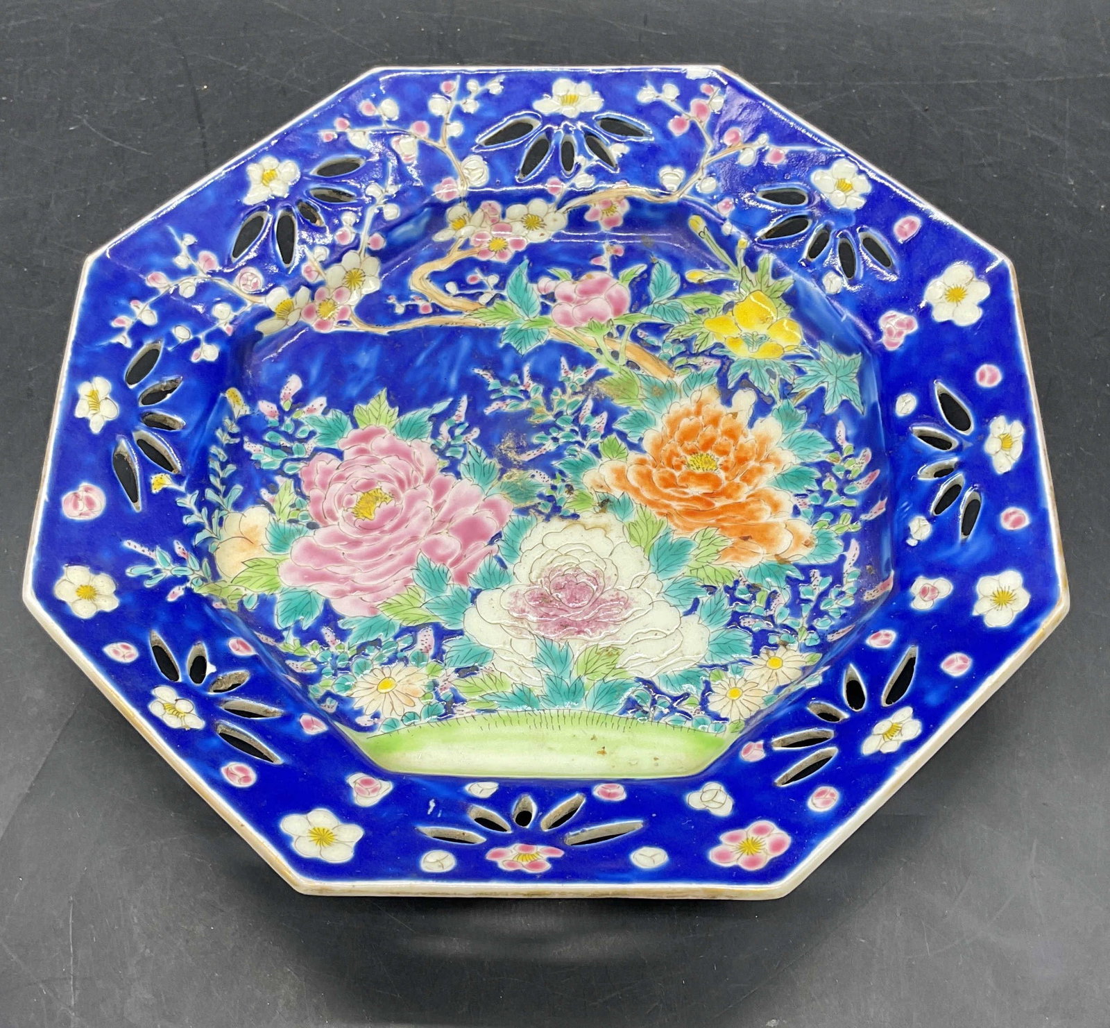 Sgn Chinese Porcelain Floral Octagonal Plate: Chinese porcelain octagonal plate with reticulated rim. Hand painted polychrome floral design on cobalt blue ground. Signed on underside. Measures approx. 7.75 x 7.75 x 1.5 inches. Some scratching. - 