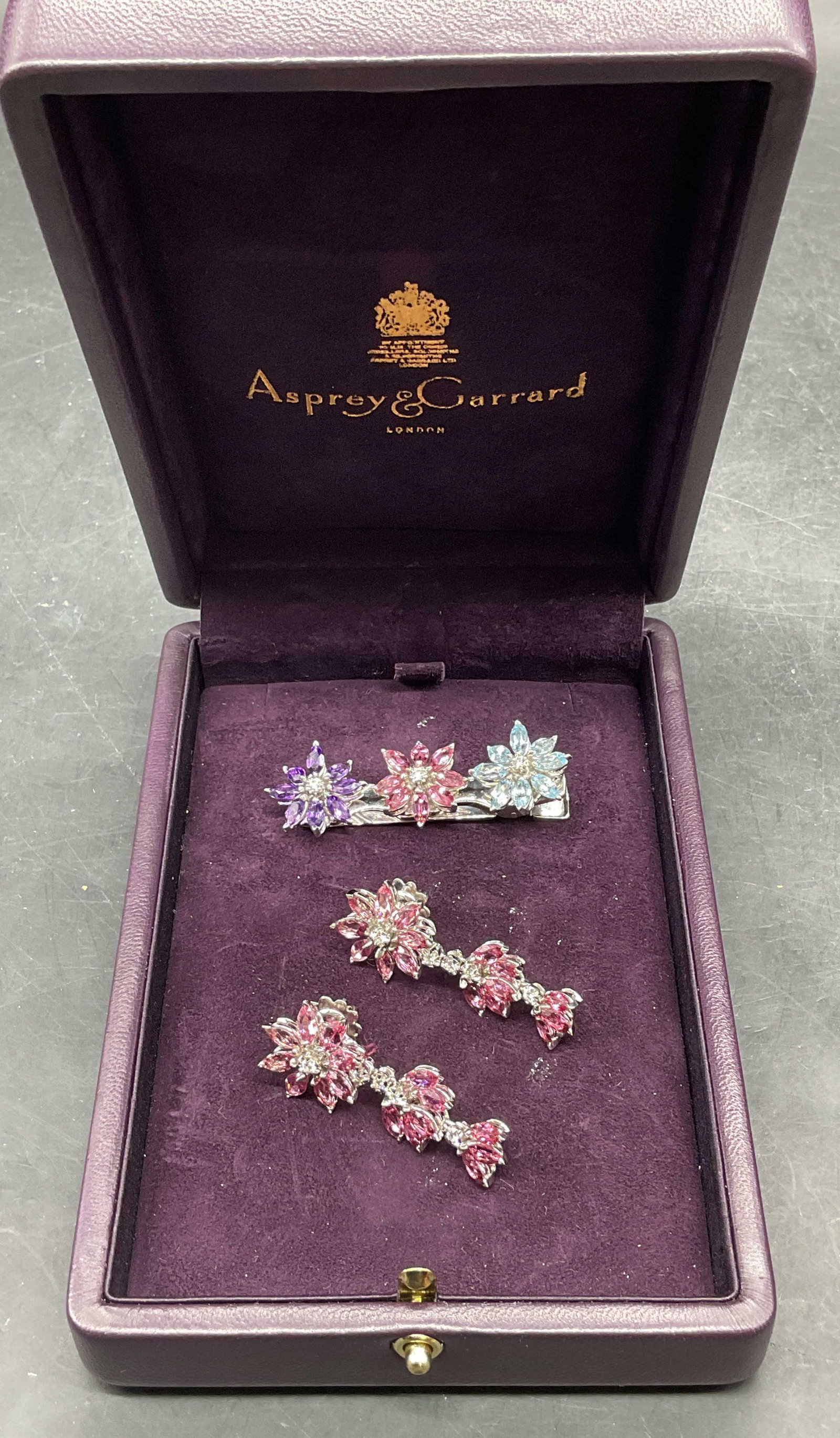 Lot 2 Asprey 18K Gold Earrings & Hair Clip 28.5 G: Lot of 2 pieces. Asprey 18k gold hair clip and earrings. Floral motifs. Earrings set with pink gemstones and diamonds, test in the range of hardness for tourmaline. Hair clip set with purple, pink,