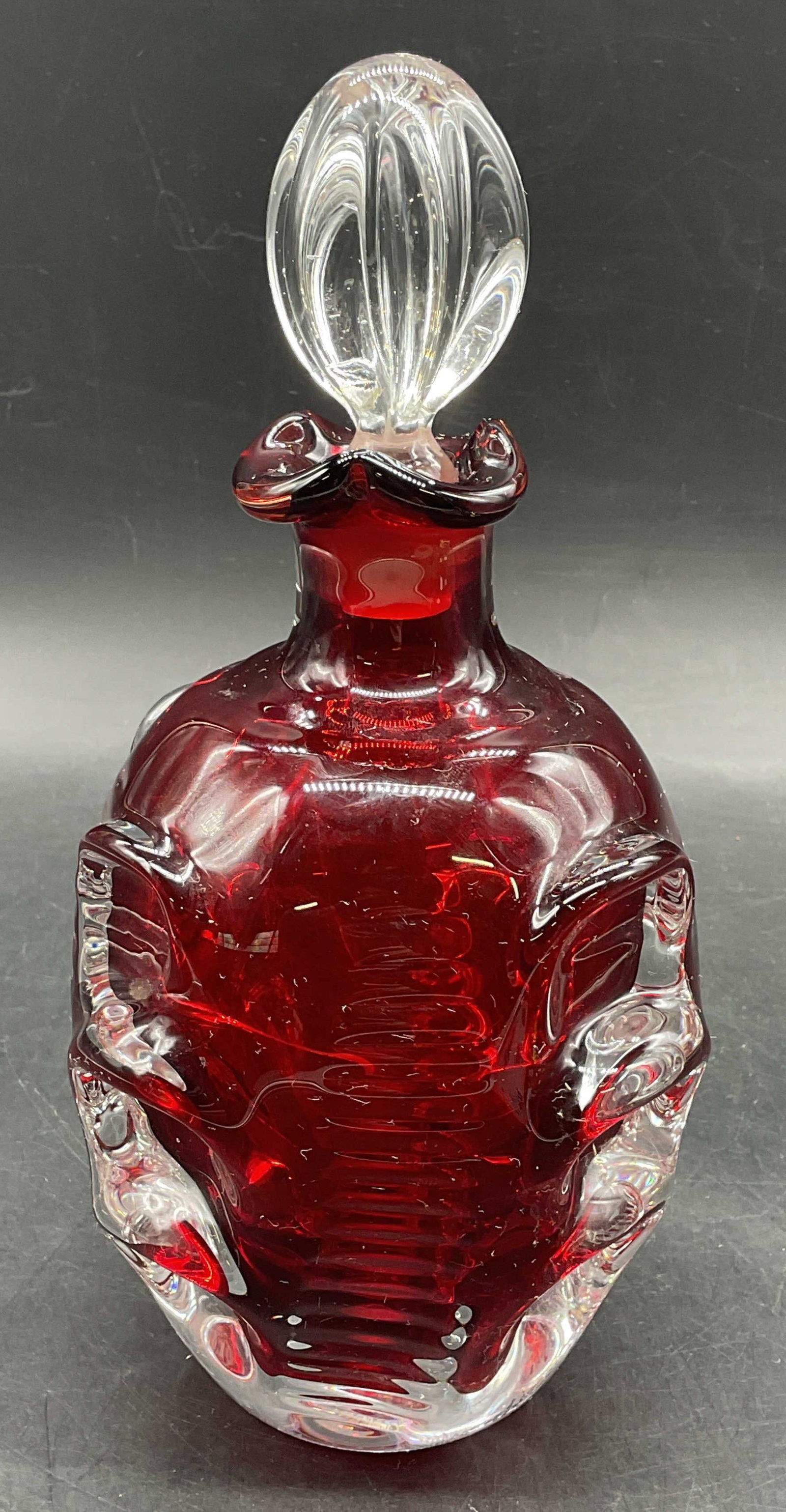 Vintage Ruby Red Art Glass Sculptural Decanter: Vintage hand blown sculptural art glass decanter. Ruby red cased glass. Measures approx. 4.5 x 6.75 excluding stopper. Hairline visible on interior, does not fully penetrate through glass. Some small