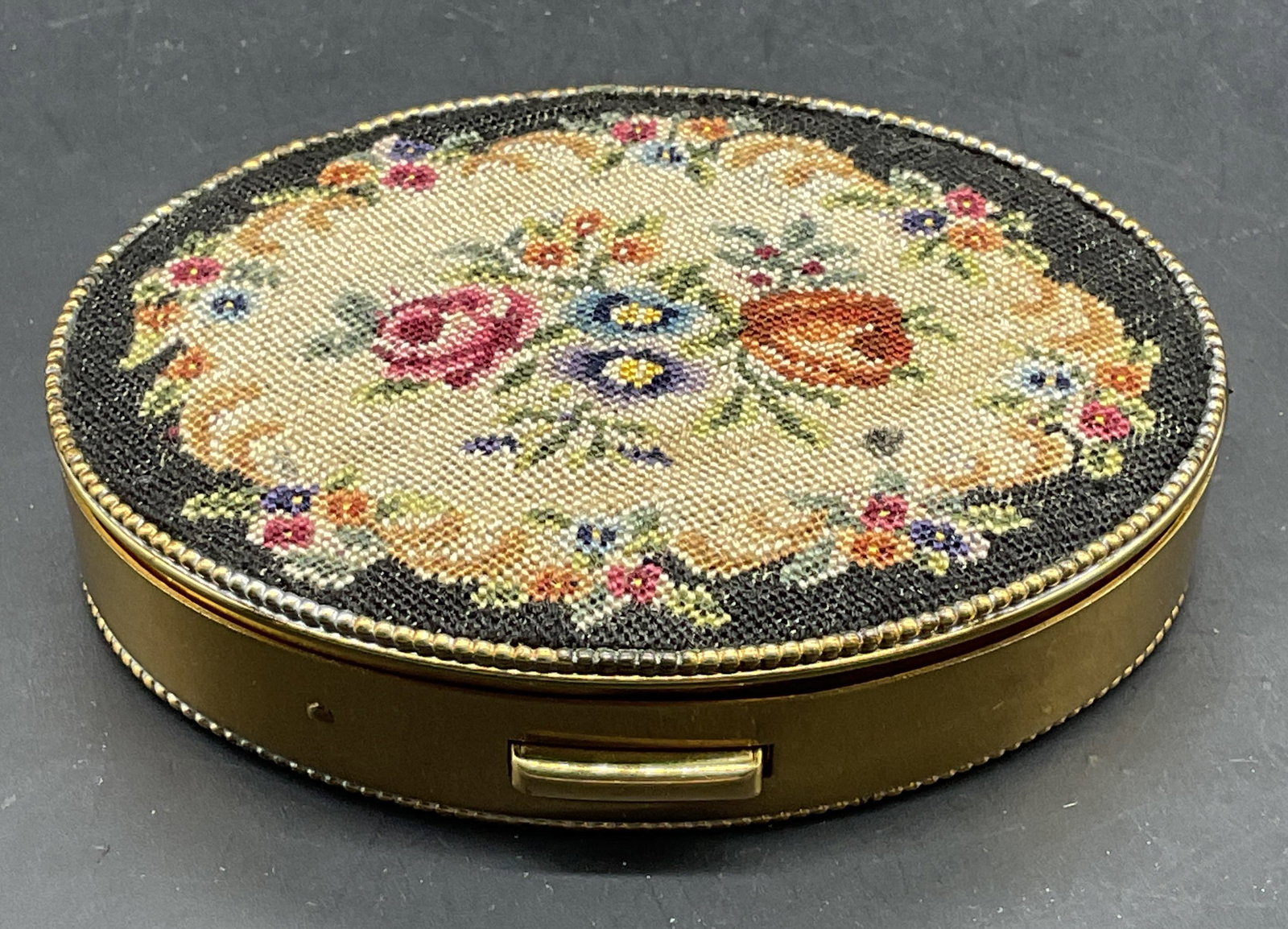 Vtg Schildkraut Petit Point Flower Compact NWOT: Vintage Schildkraut gold tone powder compact with hand stretched petit point panels. Flower motifs. Measures approx. 3 x 2 x .75 inches. Label on interior with stitch number and style number. New