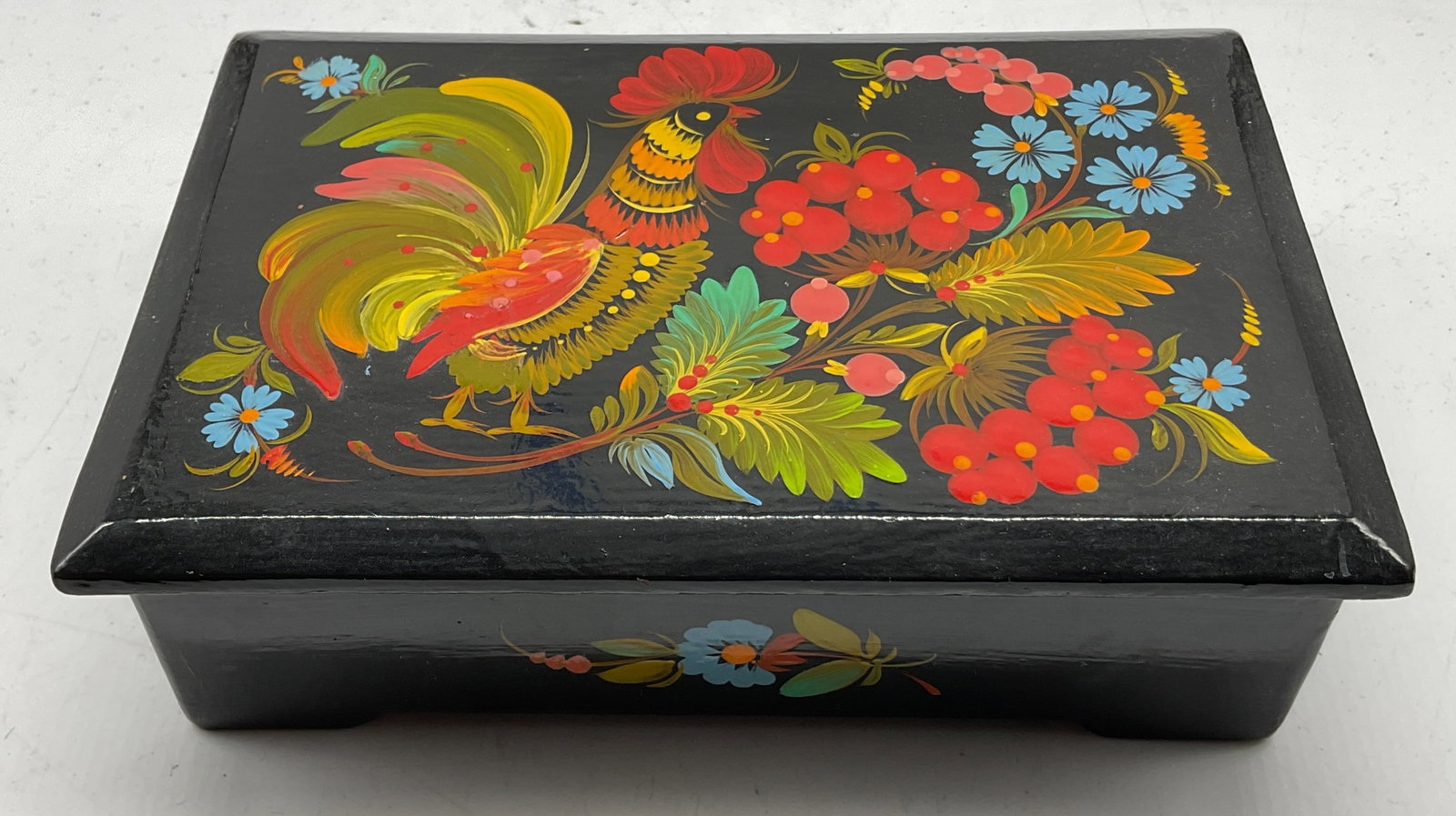 Vintage Black Wood Lacquer Trinket Box: Vintage black wood lacquered lidded trinket box. Rectangular shape. Footed on underside. Hand painted rooster and floral motifs in varying colors. Measures approx 5 x 7.5 x 2 inches. Some scratching.