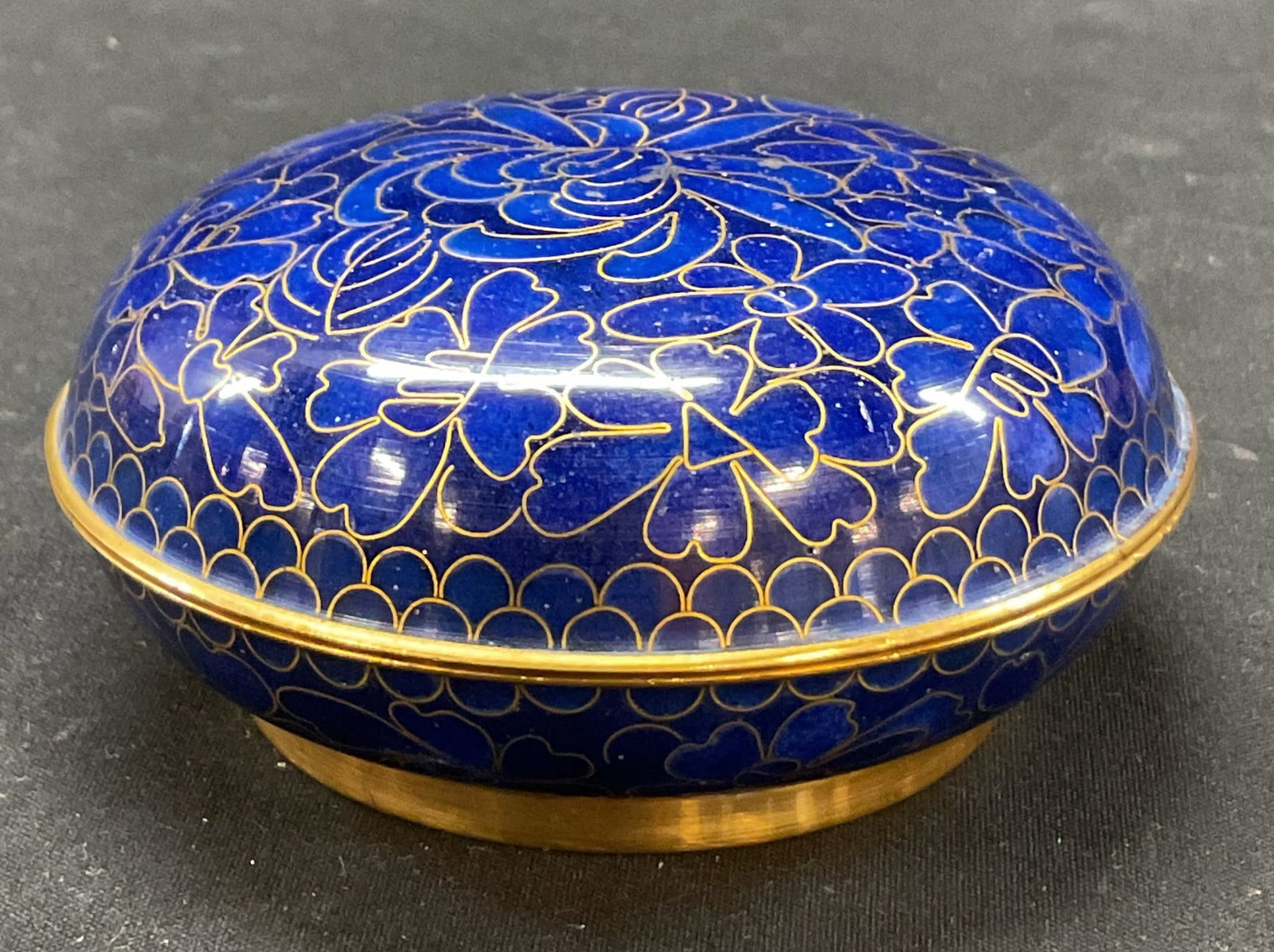 Vintage Circular Cloisonne Lidded Trinket Box: Vintage circular cloisonne lidded trinket box. Marked on underside. Enameled metal. Circular shape. Blue and gilt floral motifs. Footed base and domed lid. Measures ht approx 1.5 inches diam approx 4