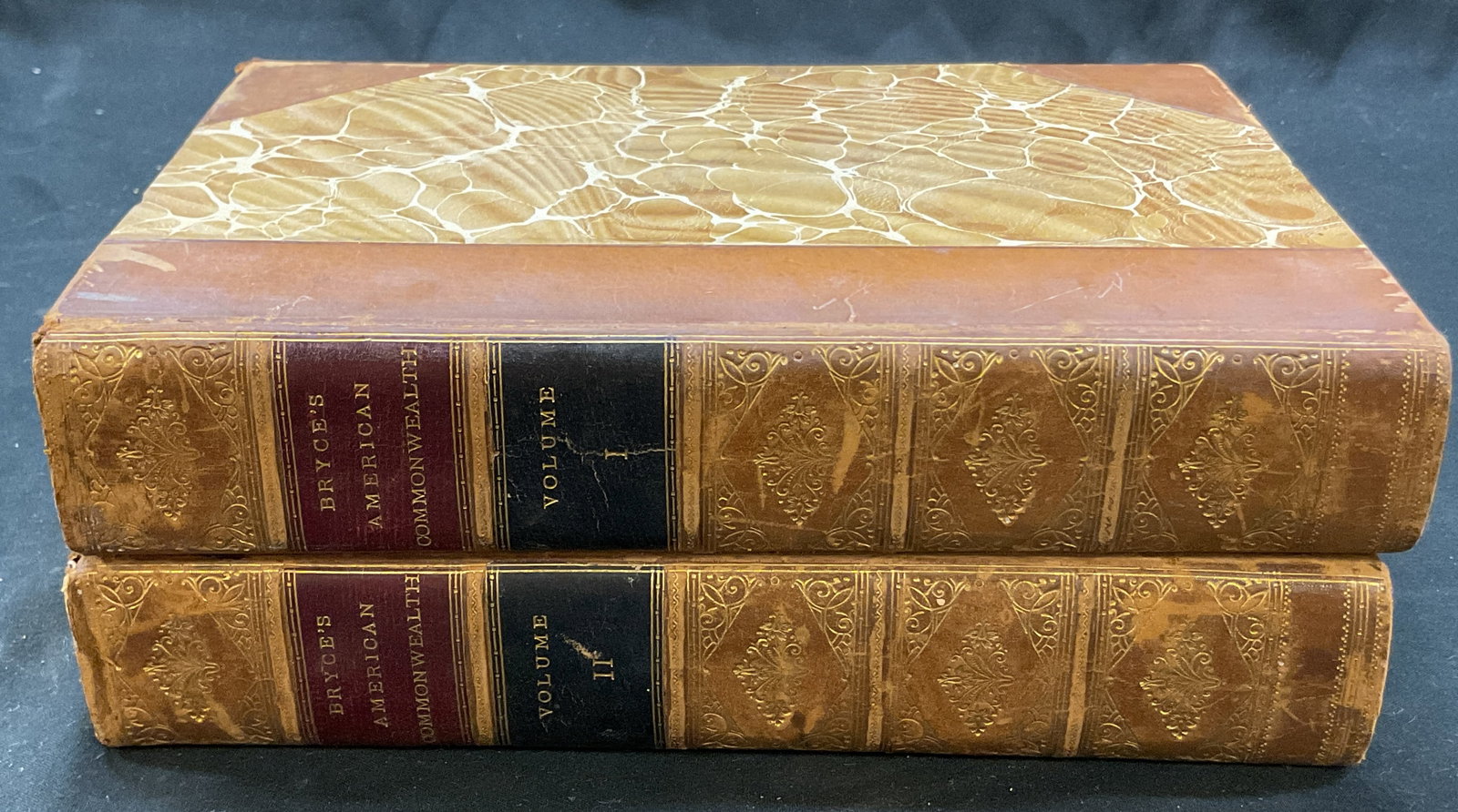 Lot 2 1889 The American Commonwealth Bryce+: The American Commonwealth volume 1 and 2. By James Bryce. Published by Macmillan & Co, 1889. Hard cover leather bound with gilt embossed trim and marble design. One book features pull out map. Measure