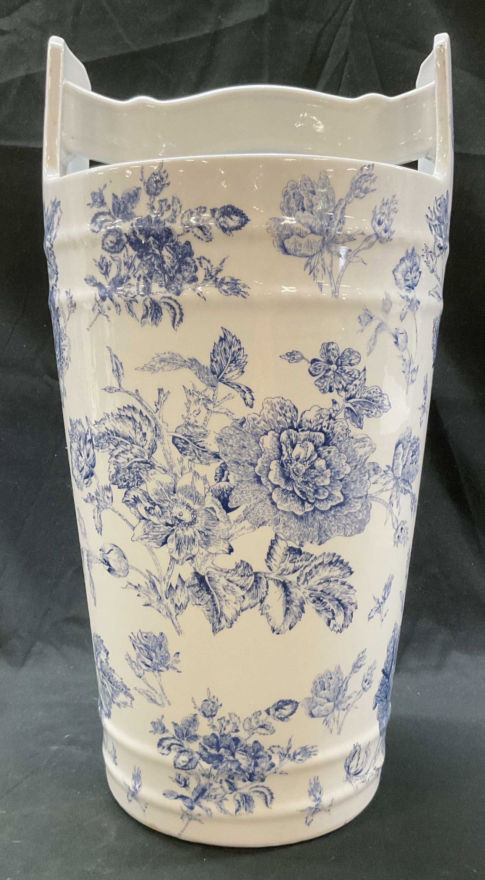 Vintage Blue & White Porcelain Umbrella Stand: Vintage blue and white porcelain umbrella stand. Tall cylinder shape. Handle across the top. Blue and white floral motifs. Measures approx 9 x 9 x 17.5 inches. Surface wear consistent with exposure. U