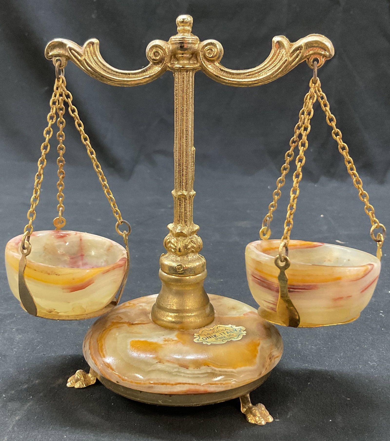 La Gioia Onyx Marble Scales Of Justice Italy: La Gioia onyx marble scales of justice. Marked La Gioia Onix Italy. Ornate brass stand. White and brown. Three claw feet on underside. Measures ht approx 6 inches diam approx 3.5 inches. Surface wear