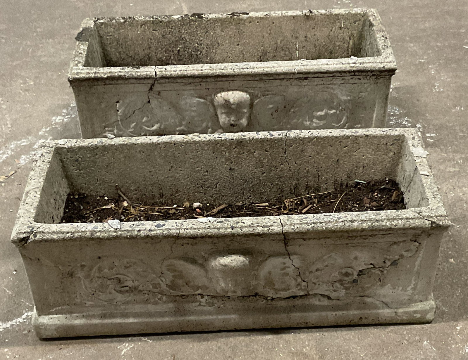 Pair Vintage Concrete Classical Cherub Planters: Pair of vintage rectangular concrete box planters with classical style cherub head reliefs. Measures approx. 19 x 7.5 x 6.5 inches. Pieces have significant weight. Wear including residue, scratching, 